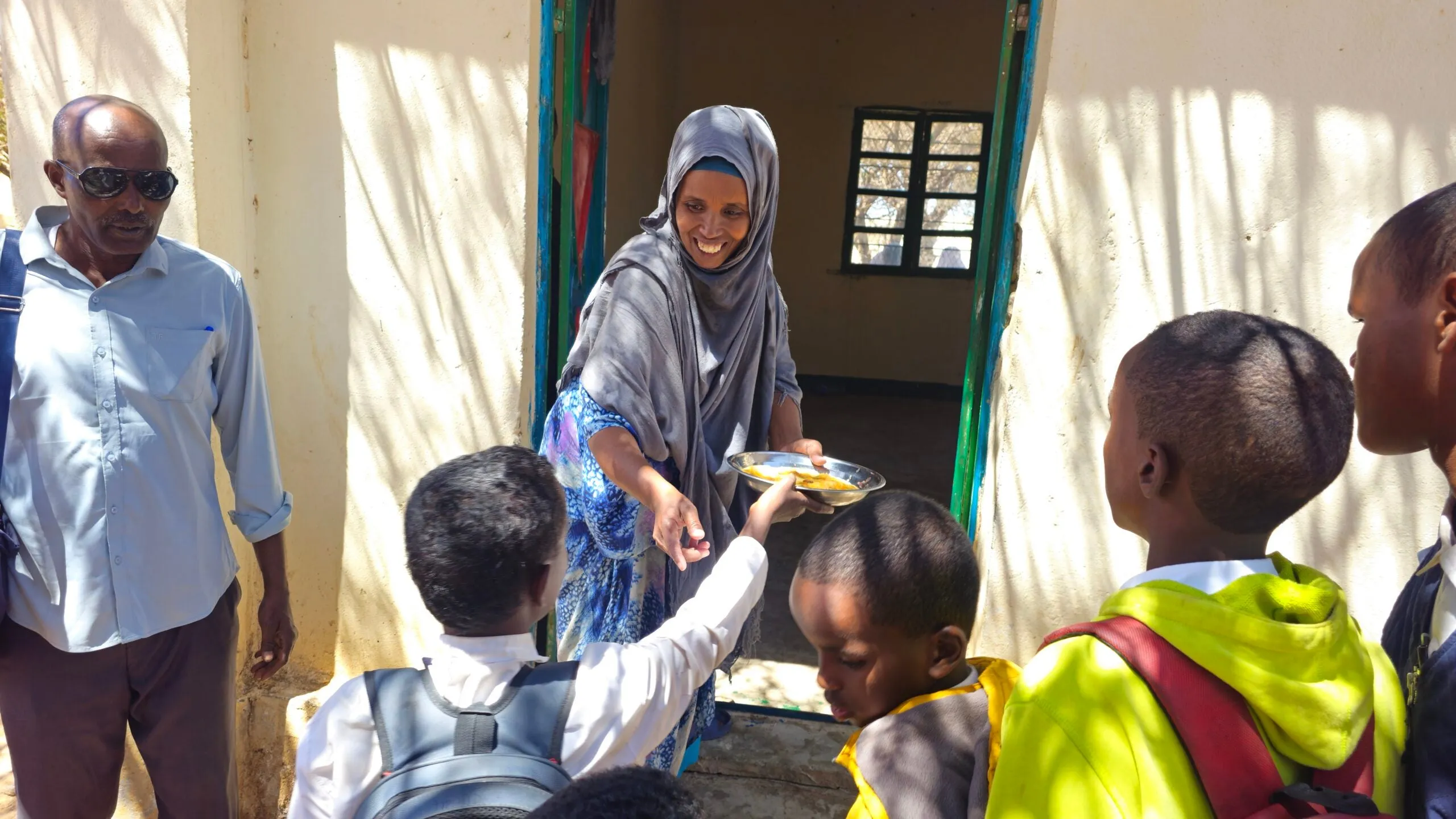 A woman distributing school mean among children in Somaliland.