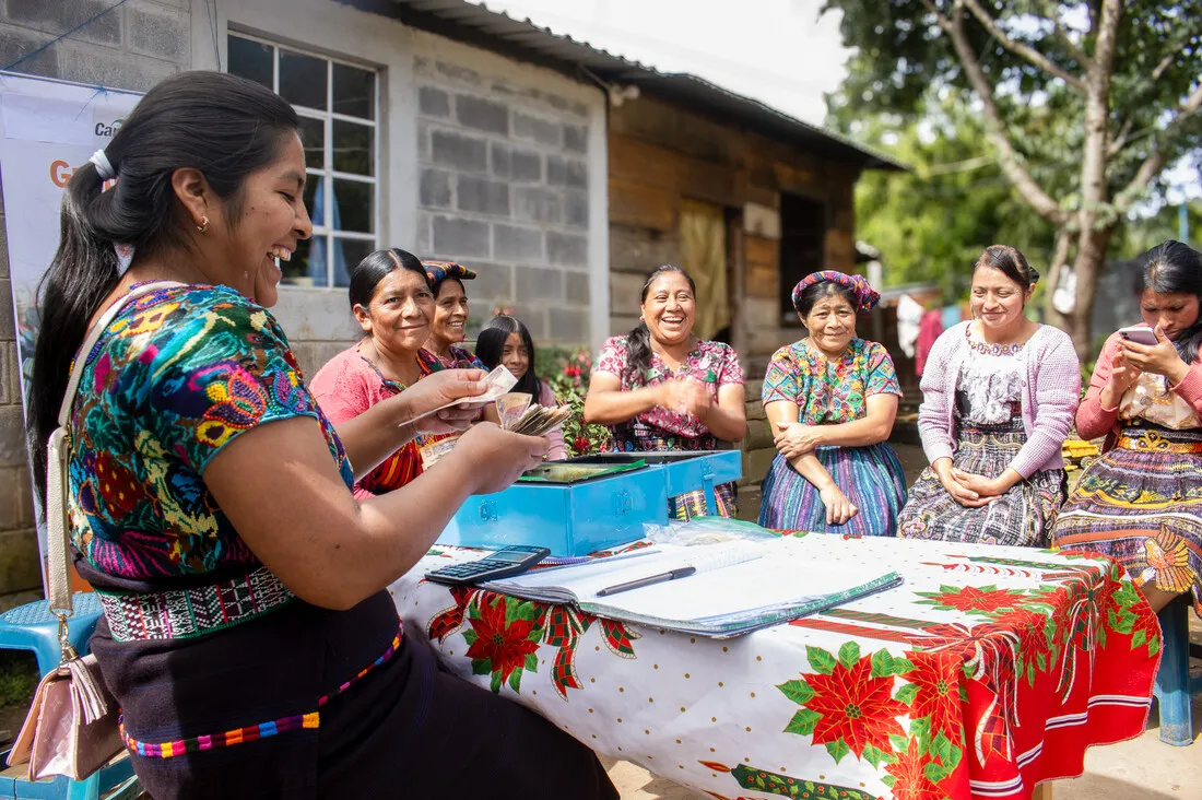 A group of women VSLA members in Ecuador laugh as they count their savings.