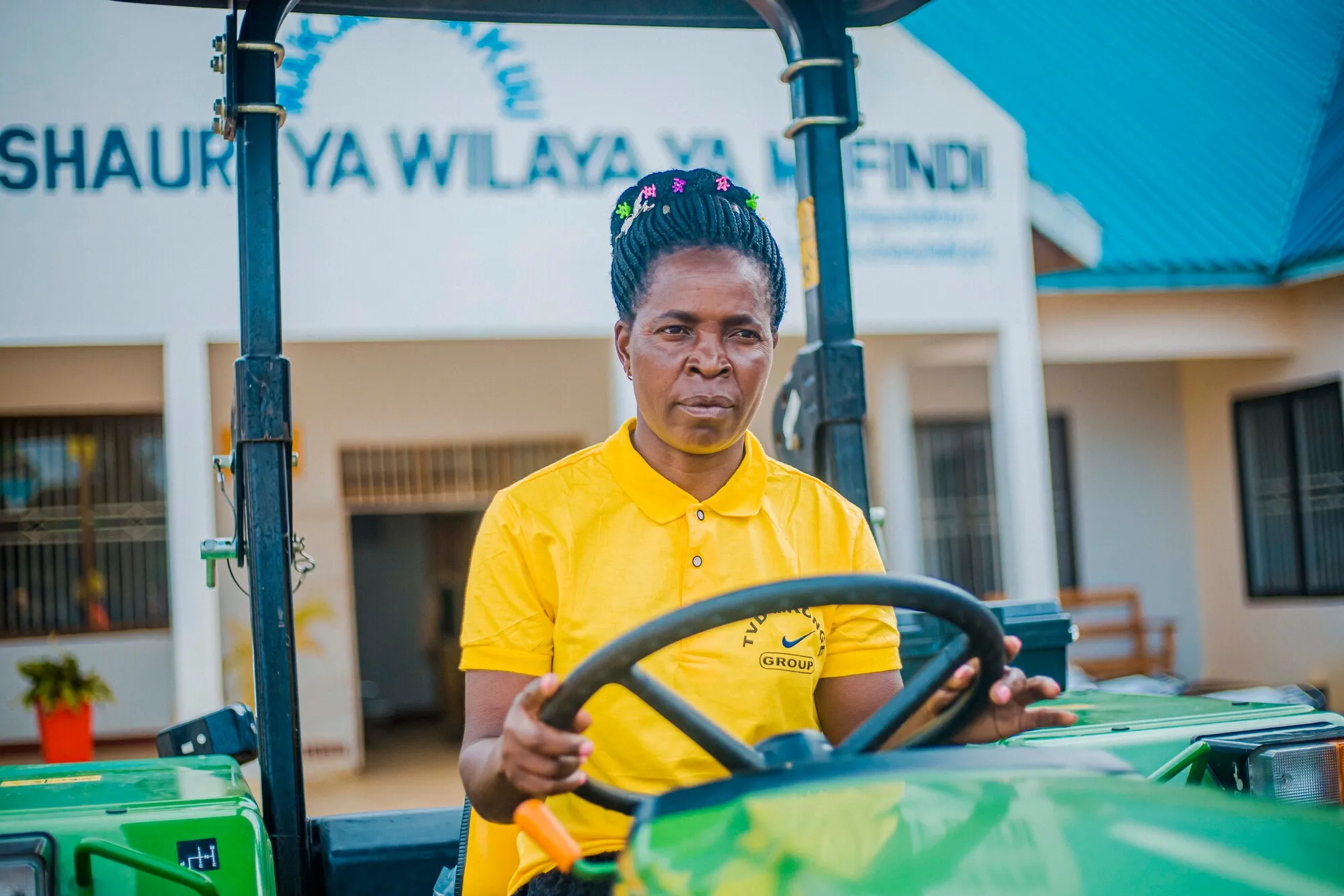 Woman VSLA member in Tanzania driving a tractor purchased through group savings.
