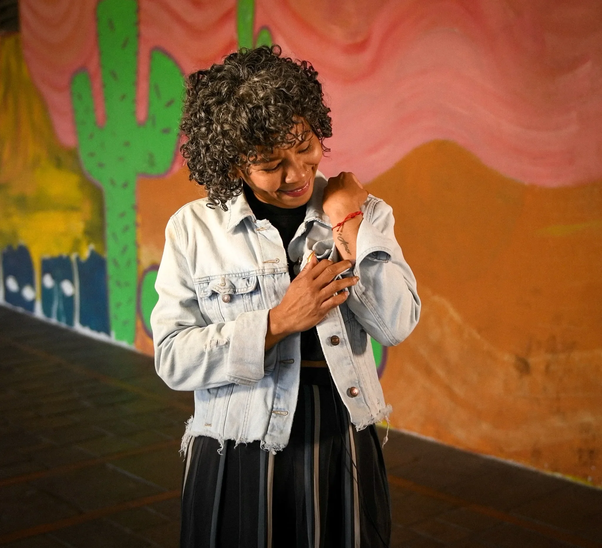 A close-up shot of a tattoo reading “+ Amor” on a woman’s wrist.