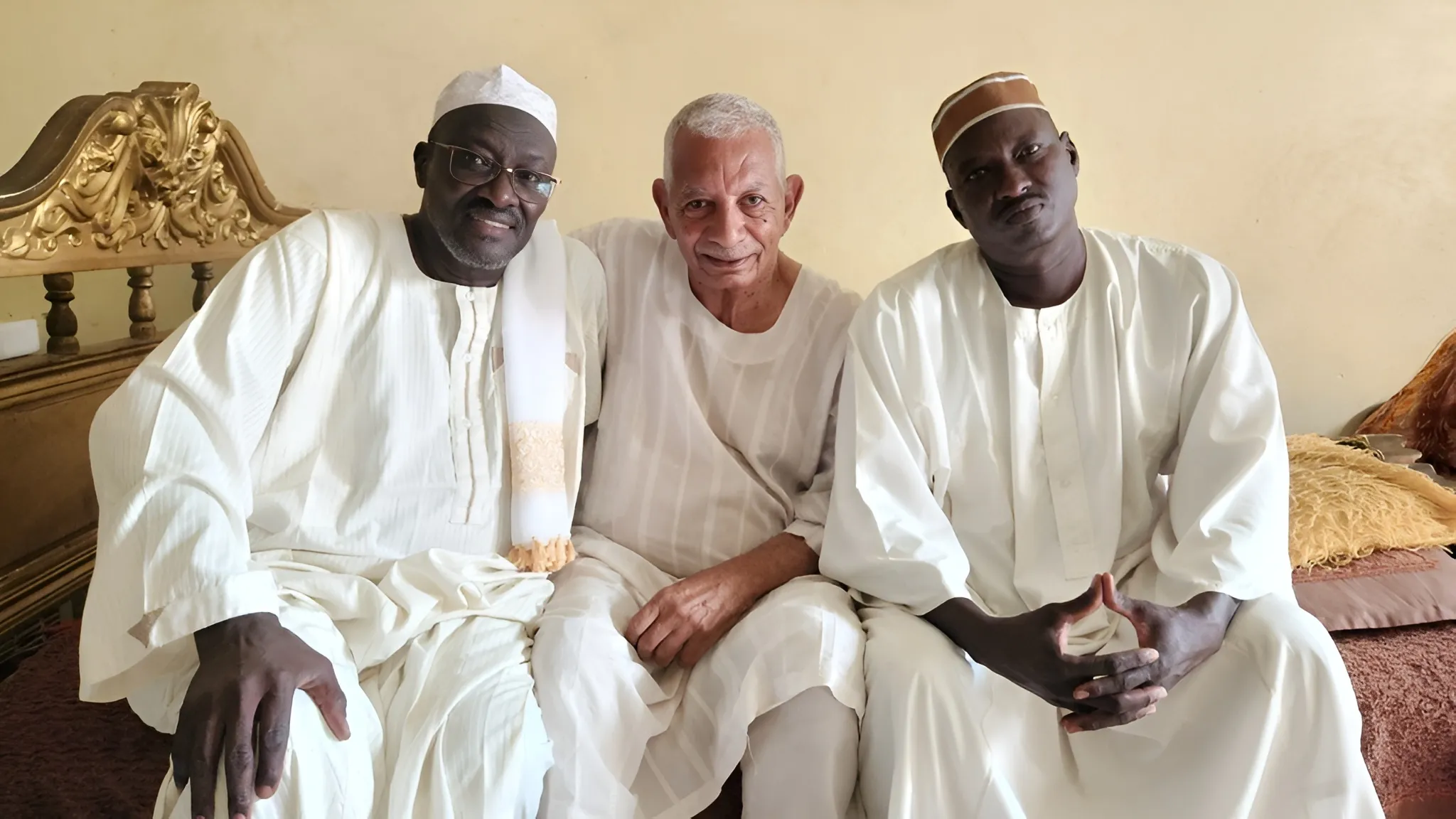 Three men sit together on a couch in Sudan.