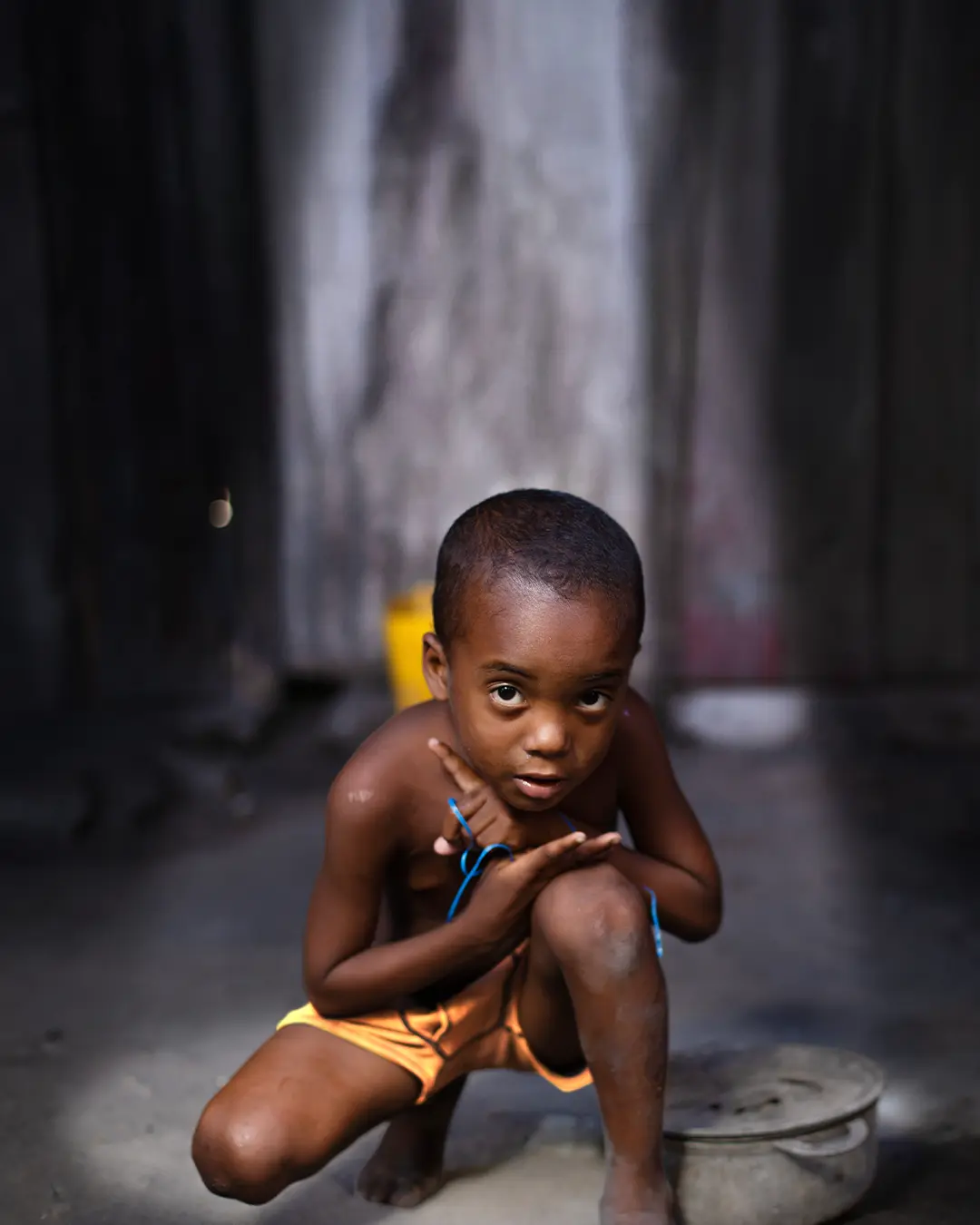 A young boy kneels on one knee and looks up at the camera.
