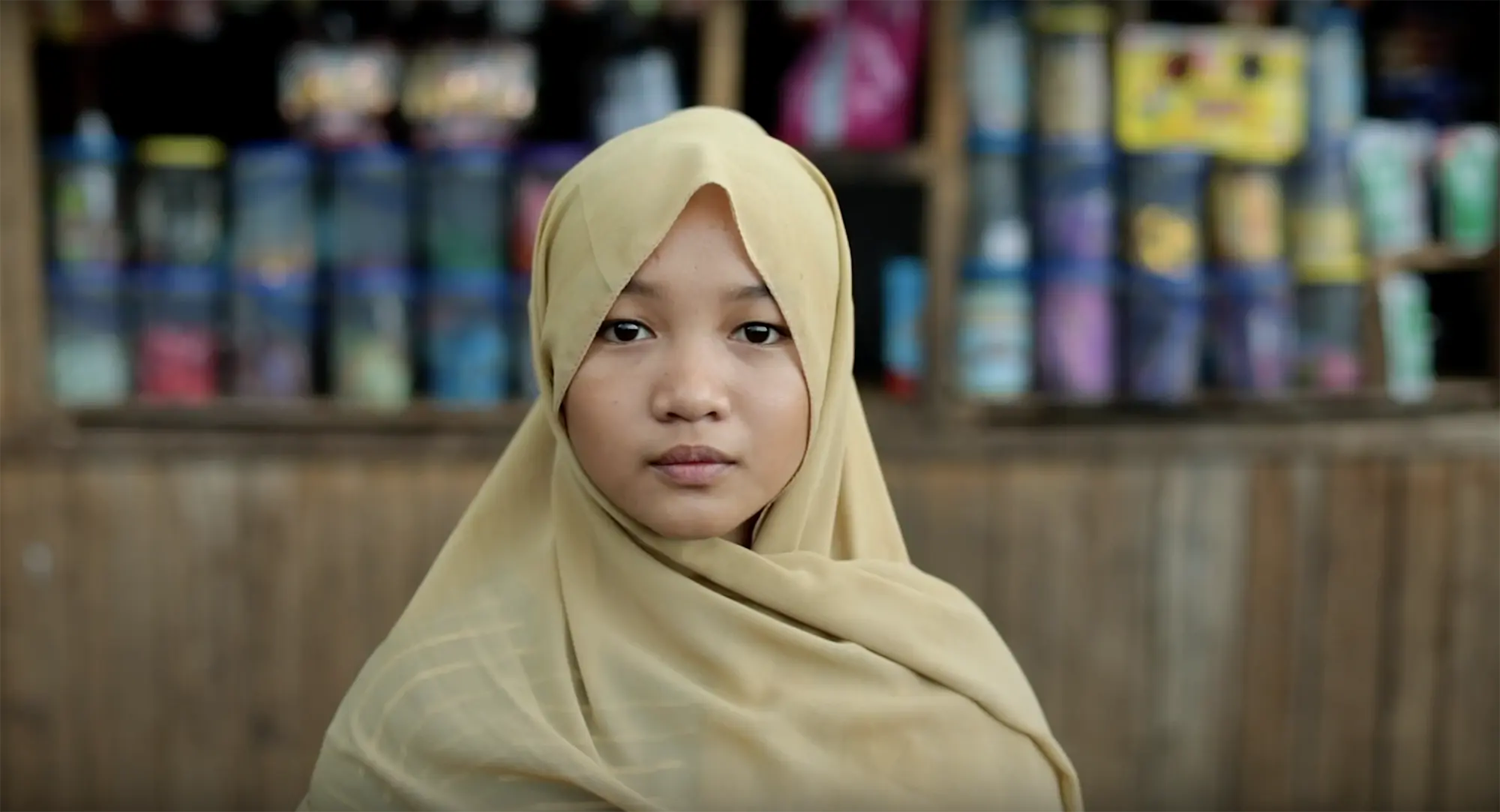 A portrait of a Filipina girl standing in front of a booth.