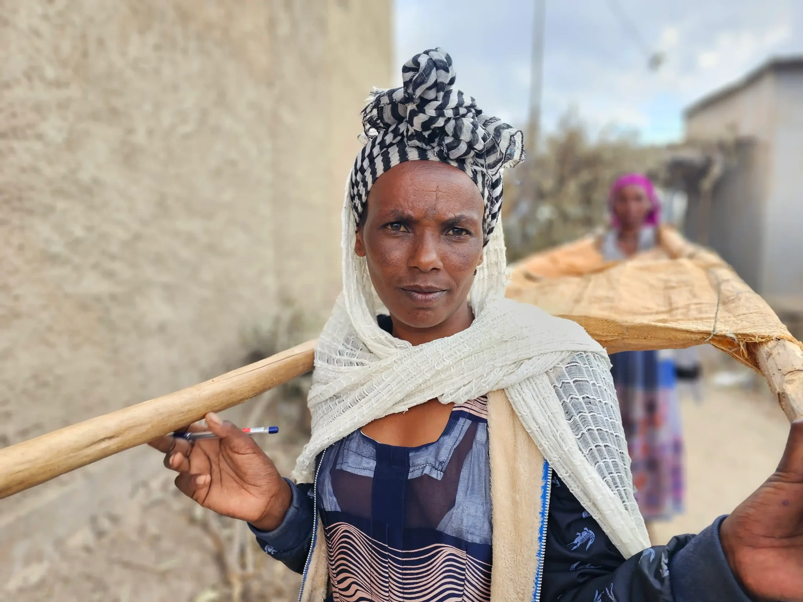 Kahsa, a woman in Tigray, Ethiopia, carries a makeshift stretcher fashioned from two wooden sticks and an old fertilizer sack used to transport mothers in labor to medical care.