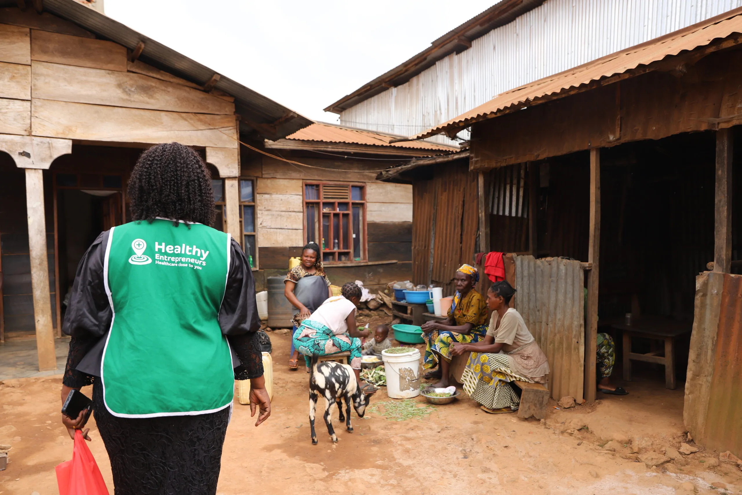 A community health worker in a green vest visits a household in North Kivu, DRC.