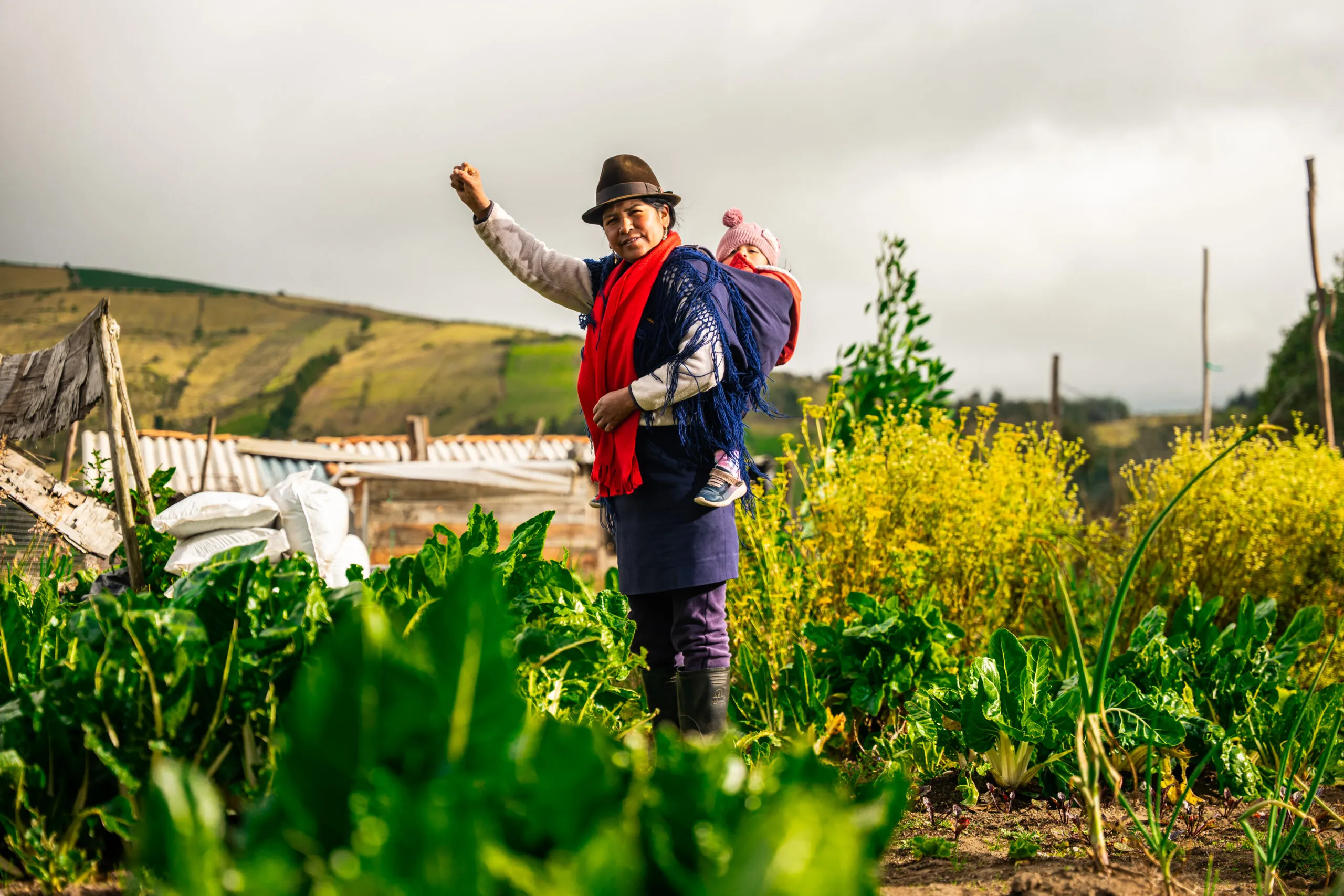 A farmer stands in a field holding her baby