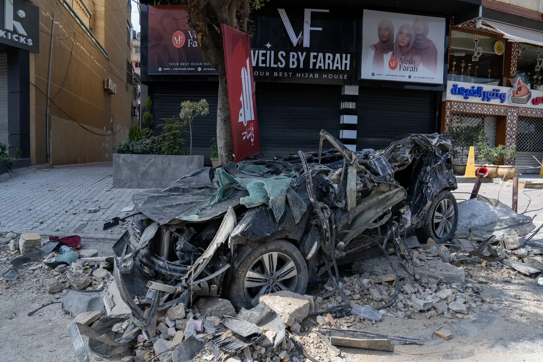 Crumpled car under debris on a street, with a closed shop named 