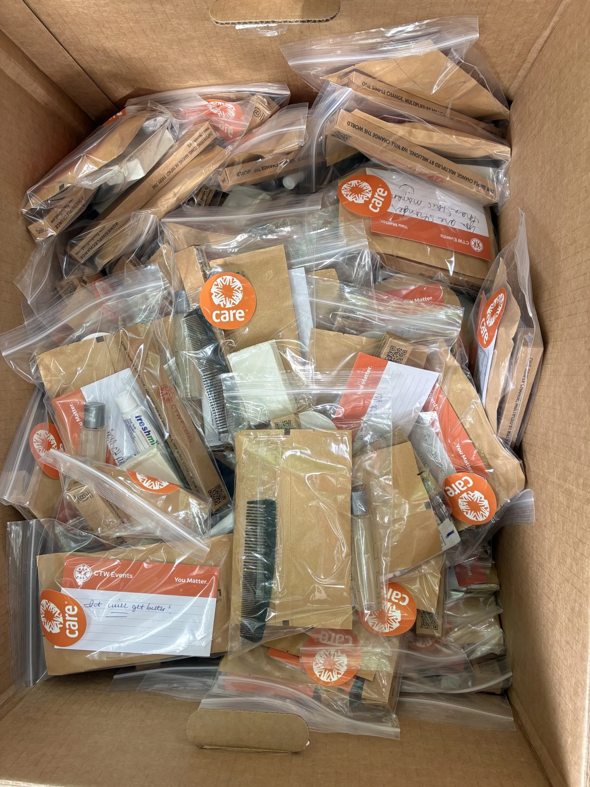 A box of CARE PACKAGE hygiene kits.