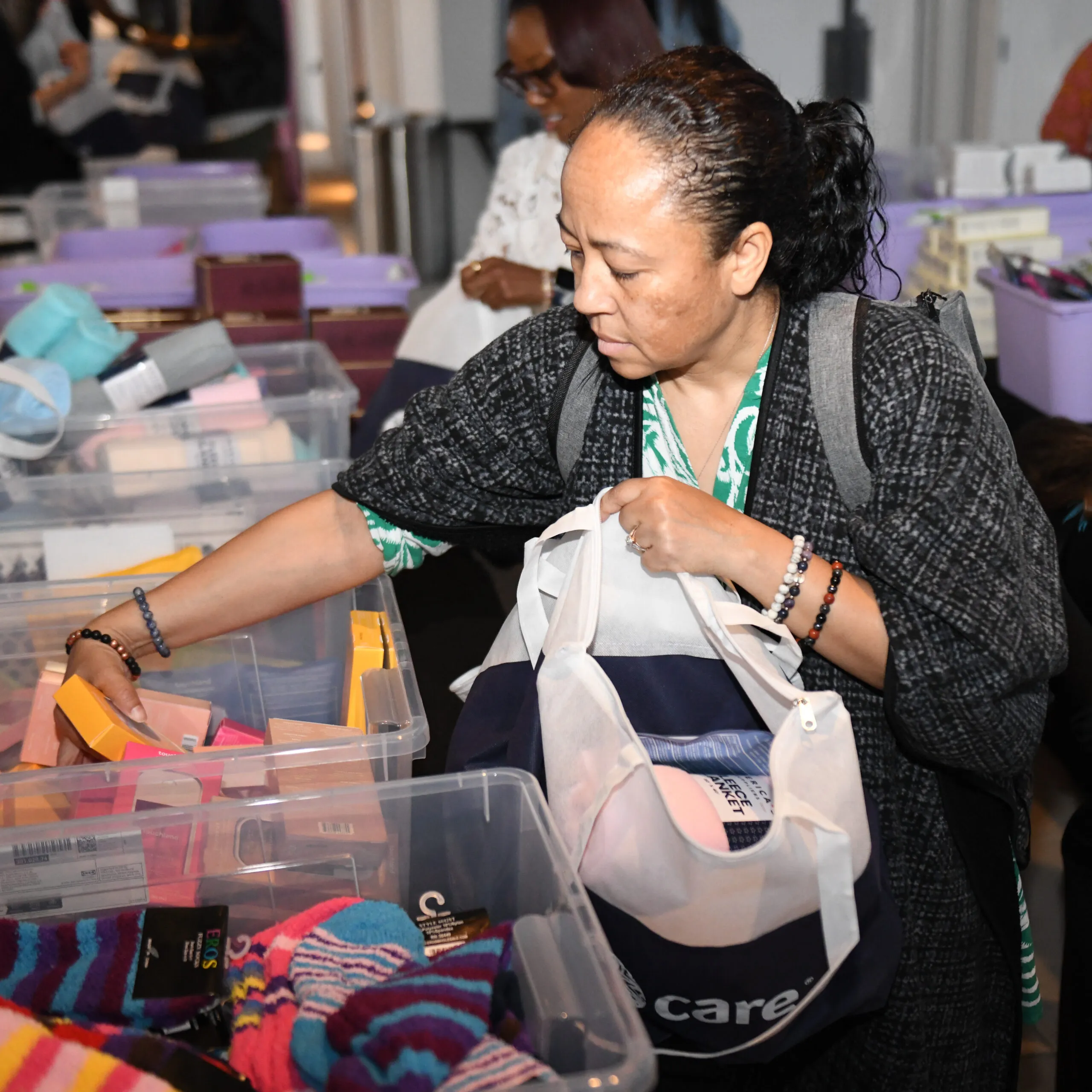 A woman picks up supplies to put inside a CARE PACKAGE for mothers and babies at a CARE event.