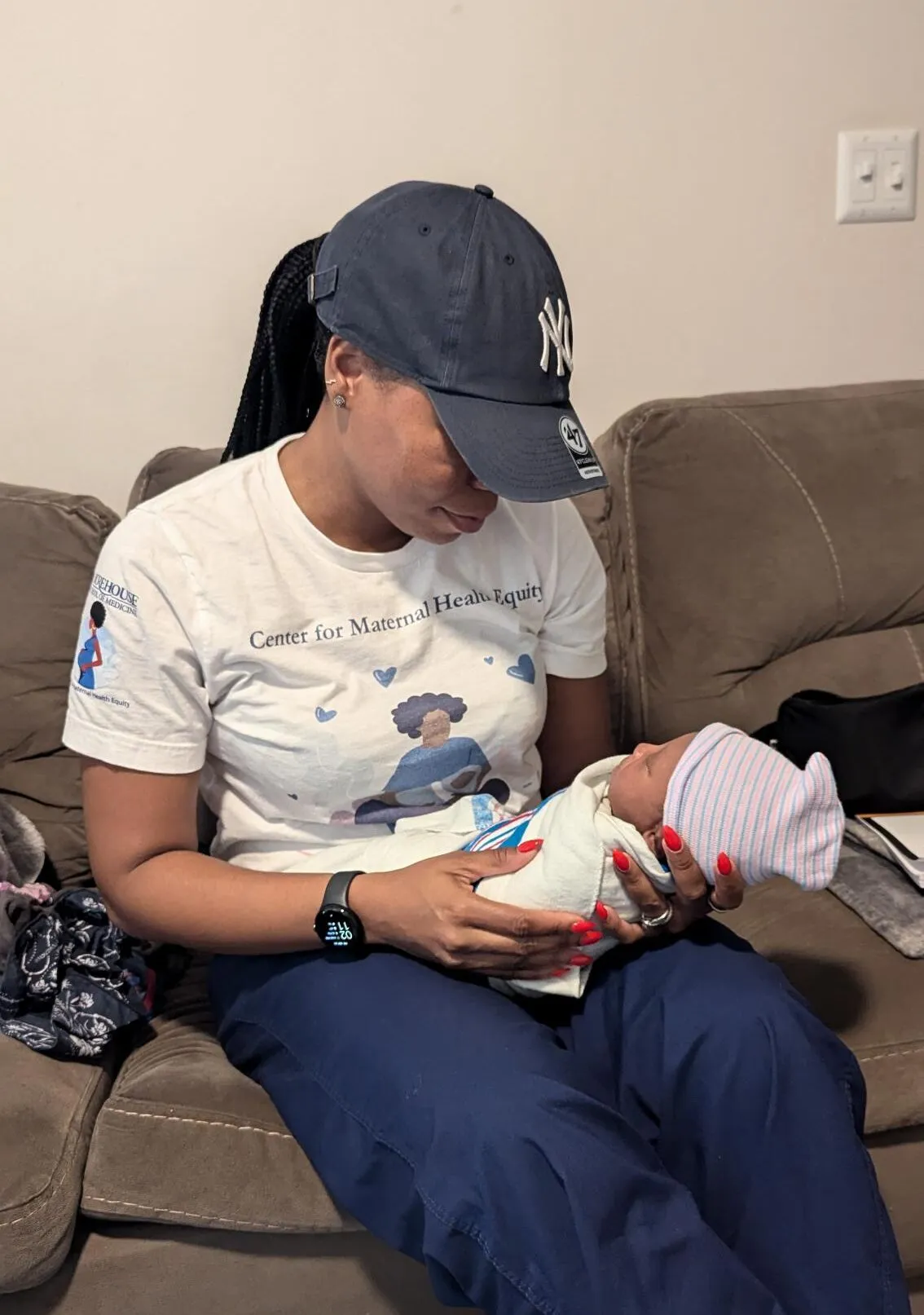A woman, childbirth educator, holds a baby on a couch.