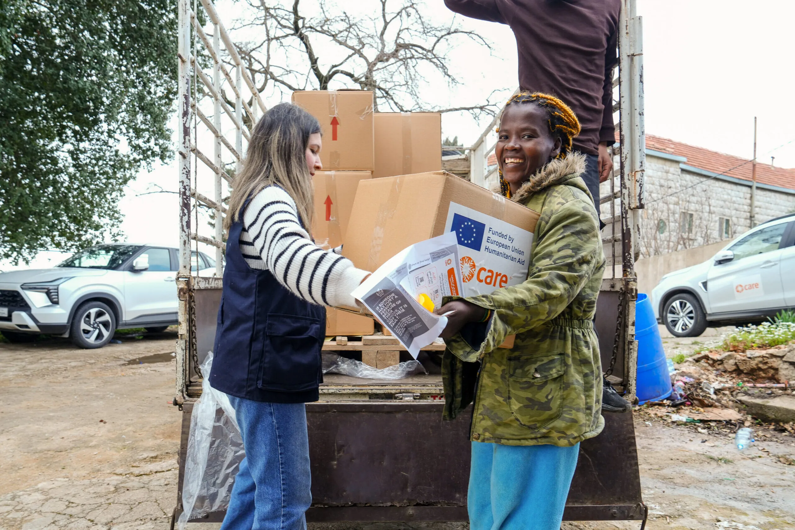 A woman smiles as she is given a CARE PACKAGE from a CARE worker.
