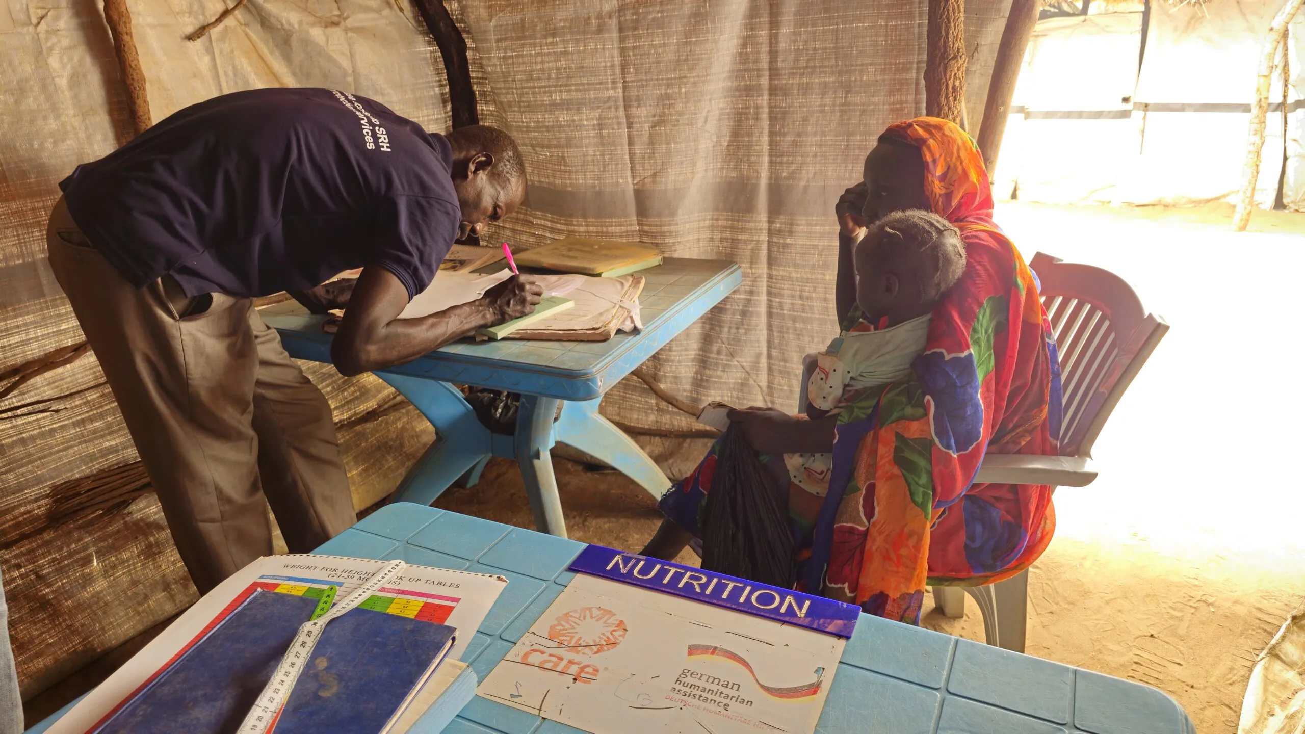 A nutritionist takes notes while speaking with a mother about her child’s treatment in South Sudan.