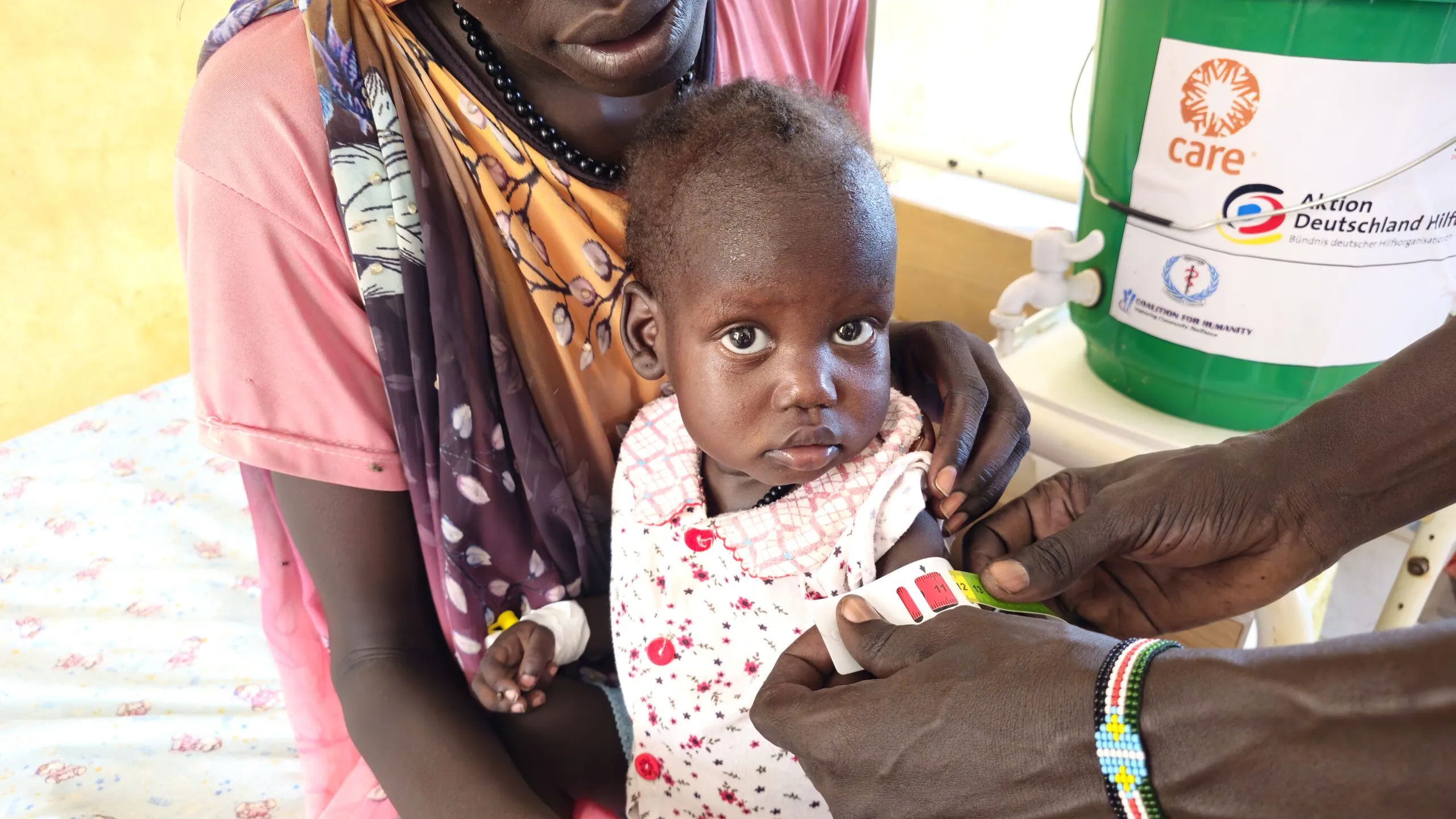 A nurse measures a young child’s upper arm with a nutrition screening band in South Sudan.