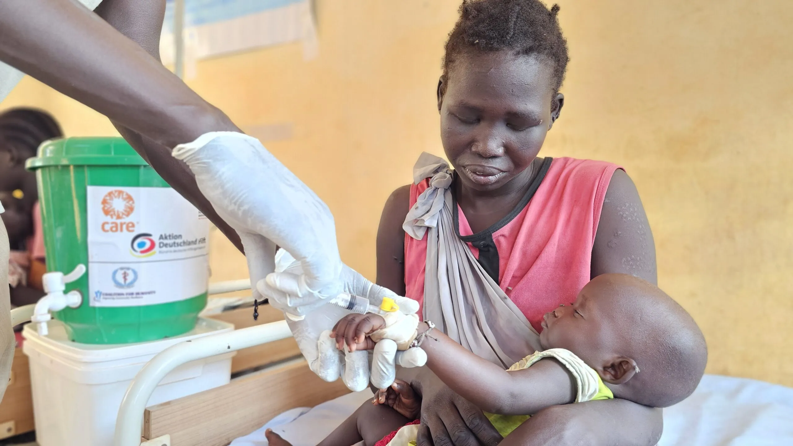 A mother holds her daughter while receiving care at a hospital in South Sudan.