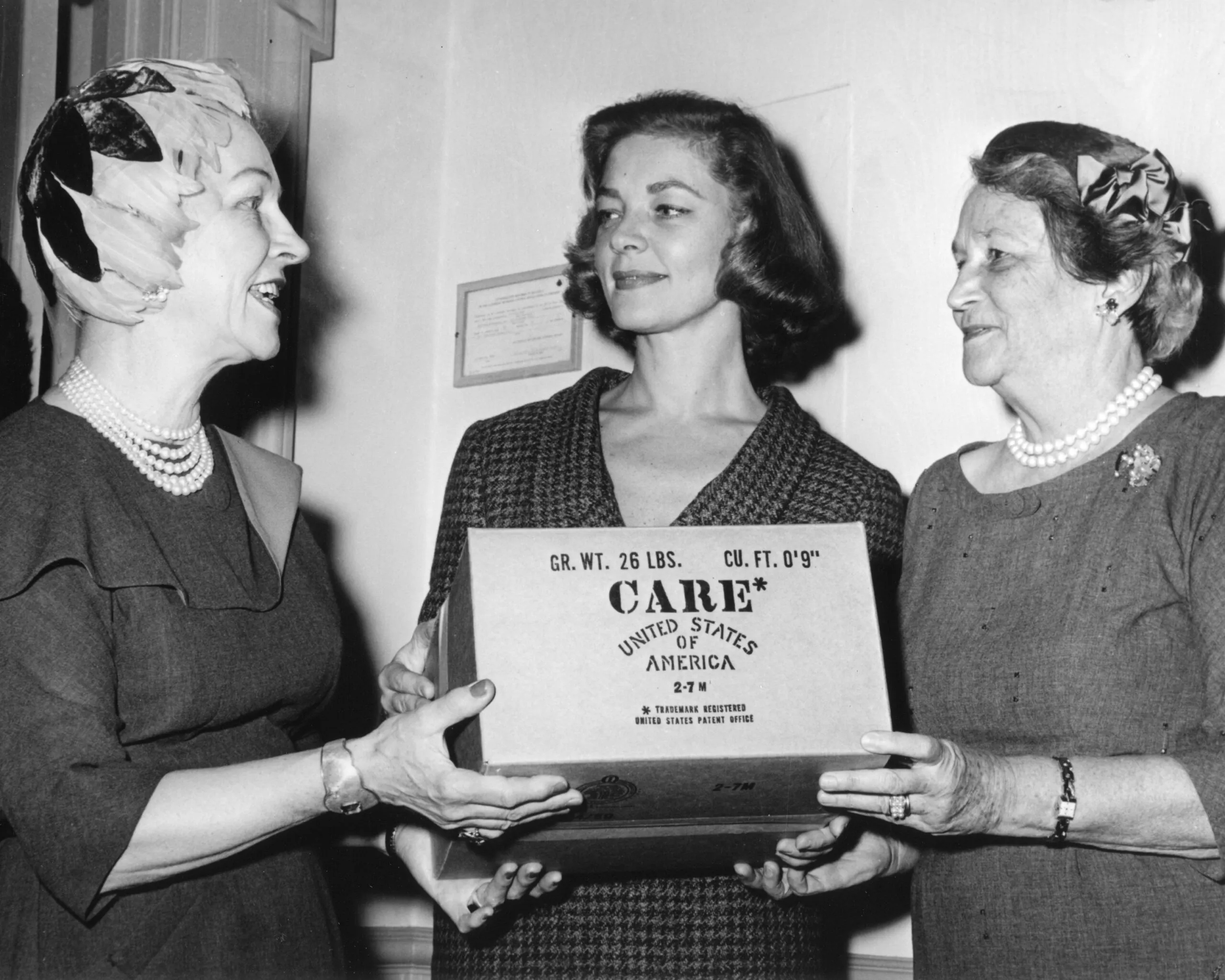 Actress Lauren Bacall and two women stand with a CARE PACKAGE.