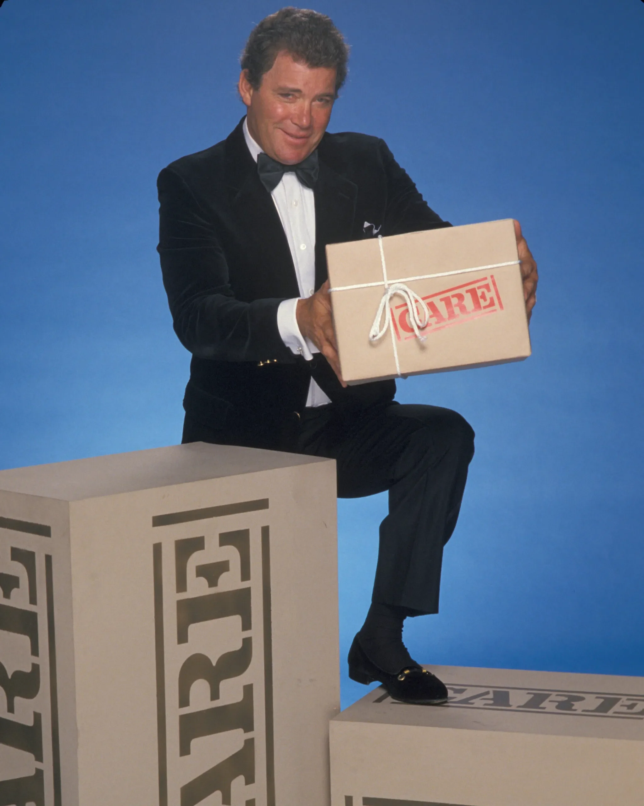 Actor William Shatner poses with a CARE PACKAGE for a television special promo.