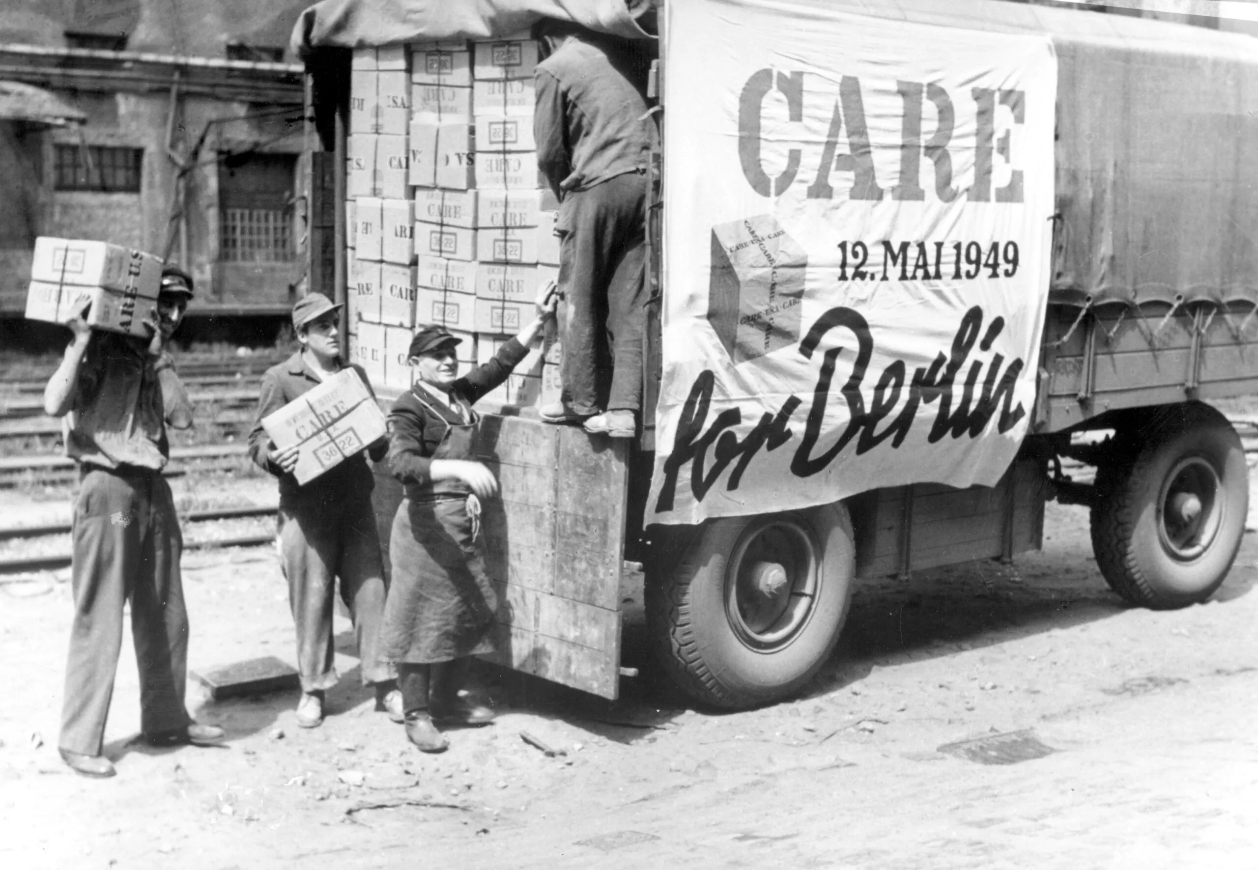 Men unloading boxes from a truck with a CARE sign on it.
