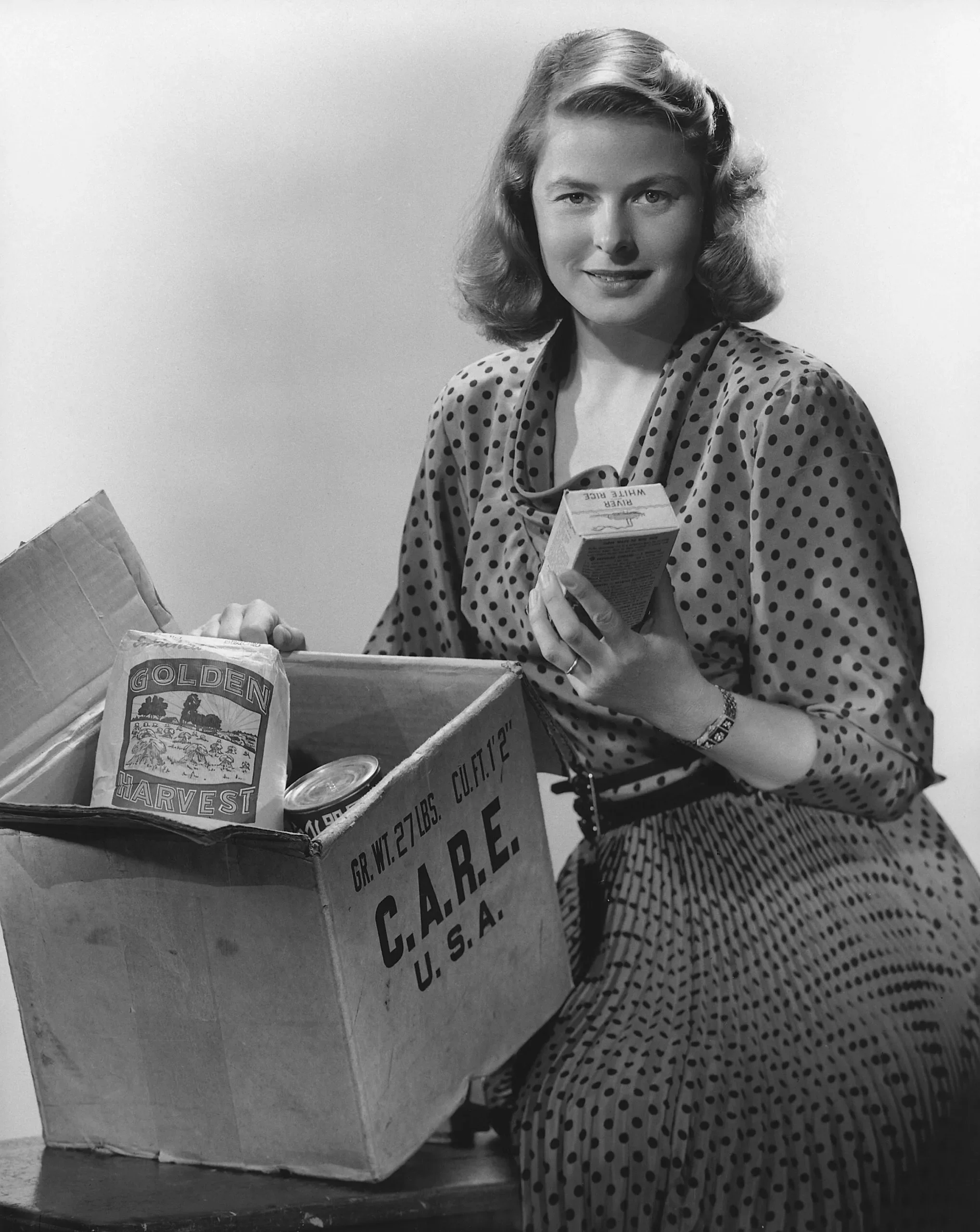 Actress Ingrid Bergman poses next to a CARE PACKAGE.