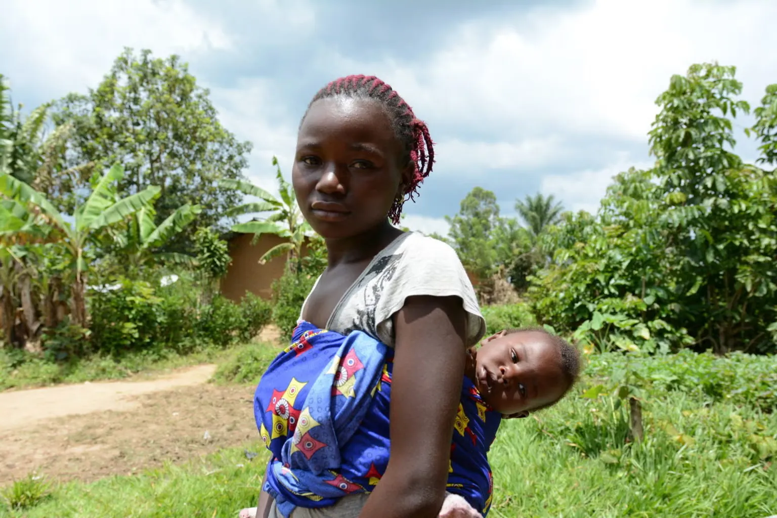A mother holds a baby outside a home in the DRC during the 2018 Ebola outbreak.