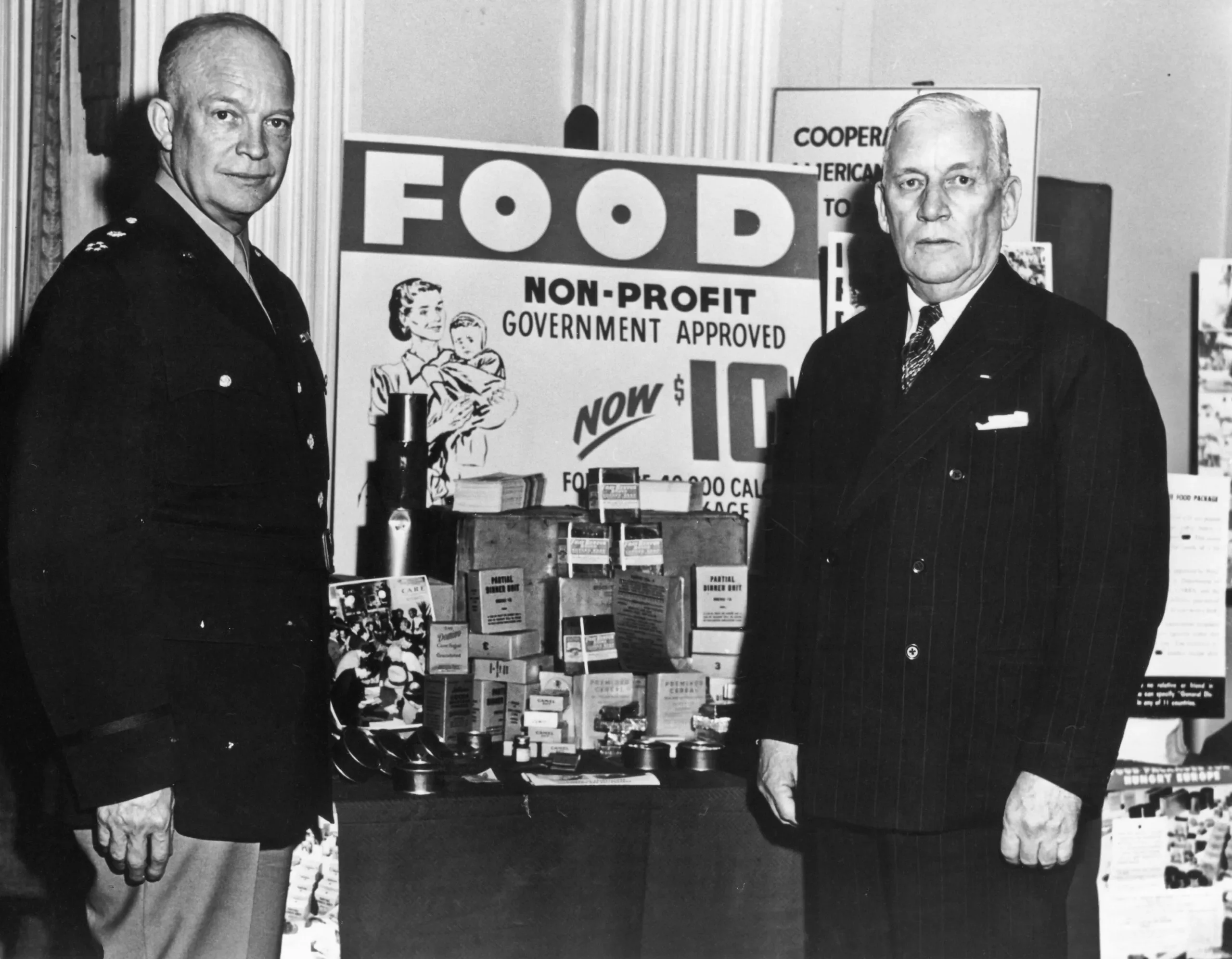 General Dwight D. Eisenhower and the Executive Director of CARE in the 1940s stand by a poster about donating food to a non-profit.