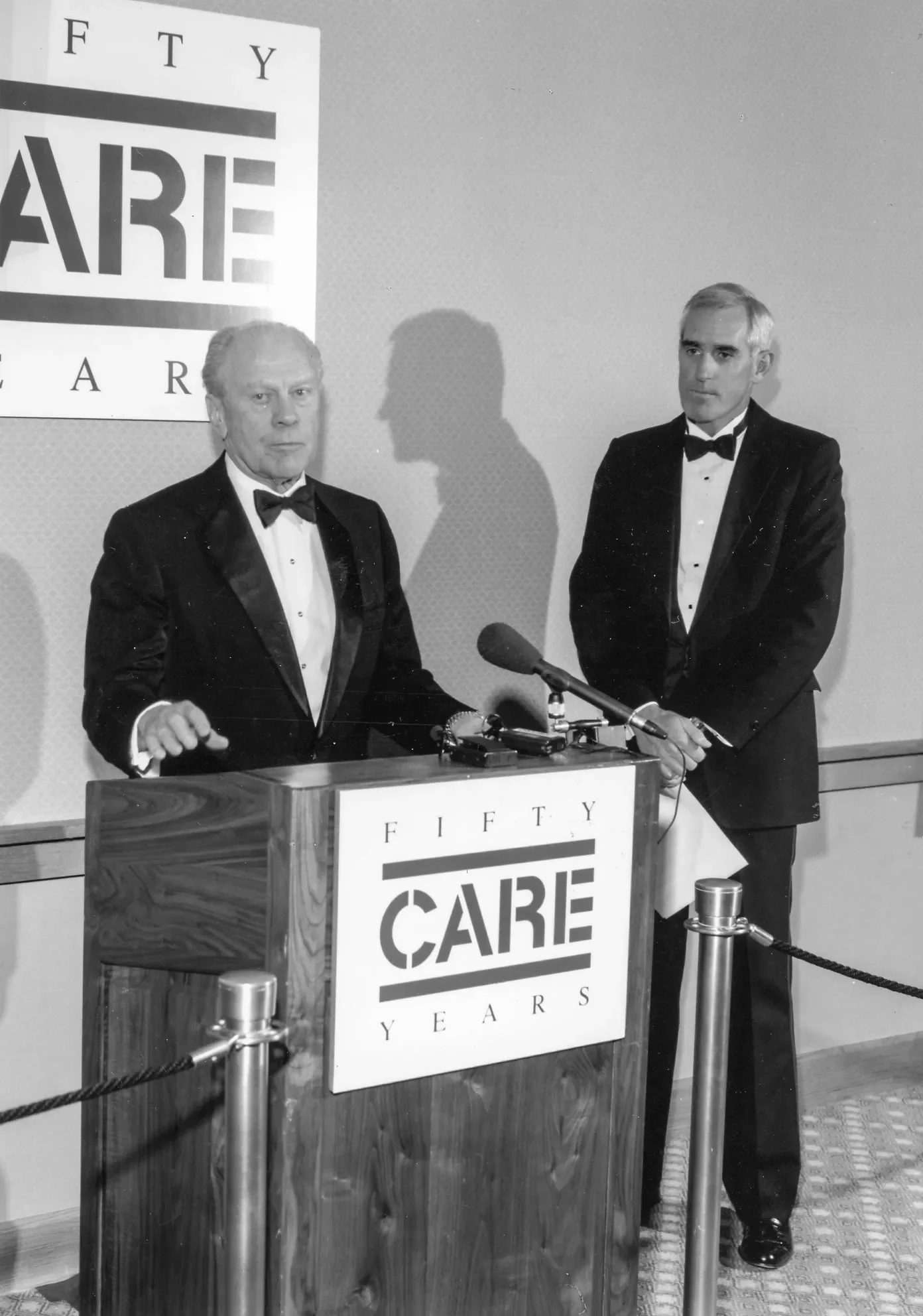 President Gerald Ford stands at a podium speaking at CARE’s 50 anniversary celebration.