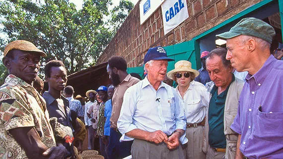 President Jimmy Carter standing with a group of people outside a CARE program building.