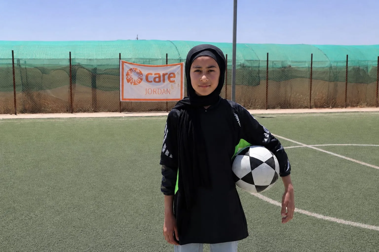 Young girl holding a soccer ball while standing on field.