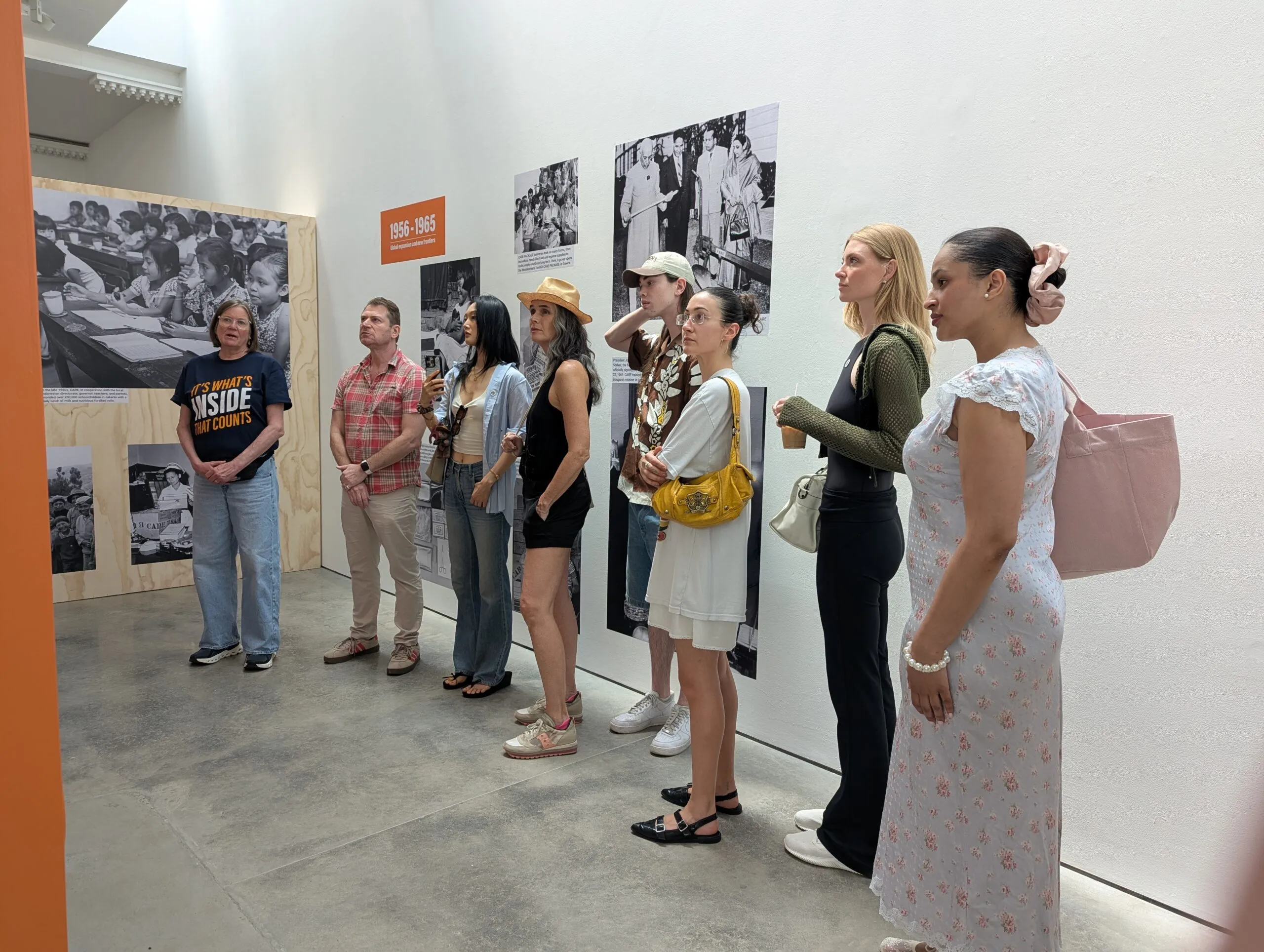 A group of people standing in a museum, reading exhibit.