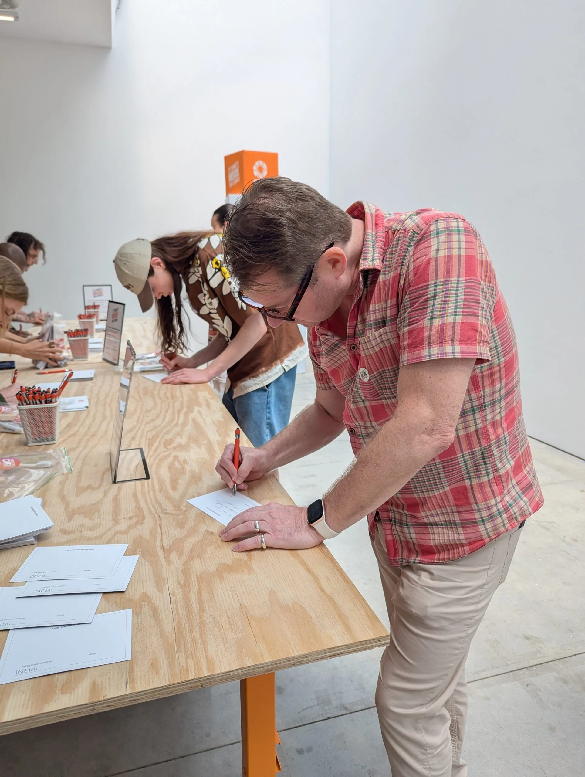 A man standing by a table writing a note.