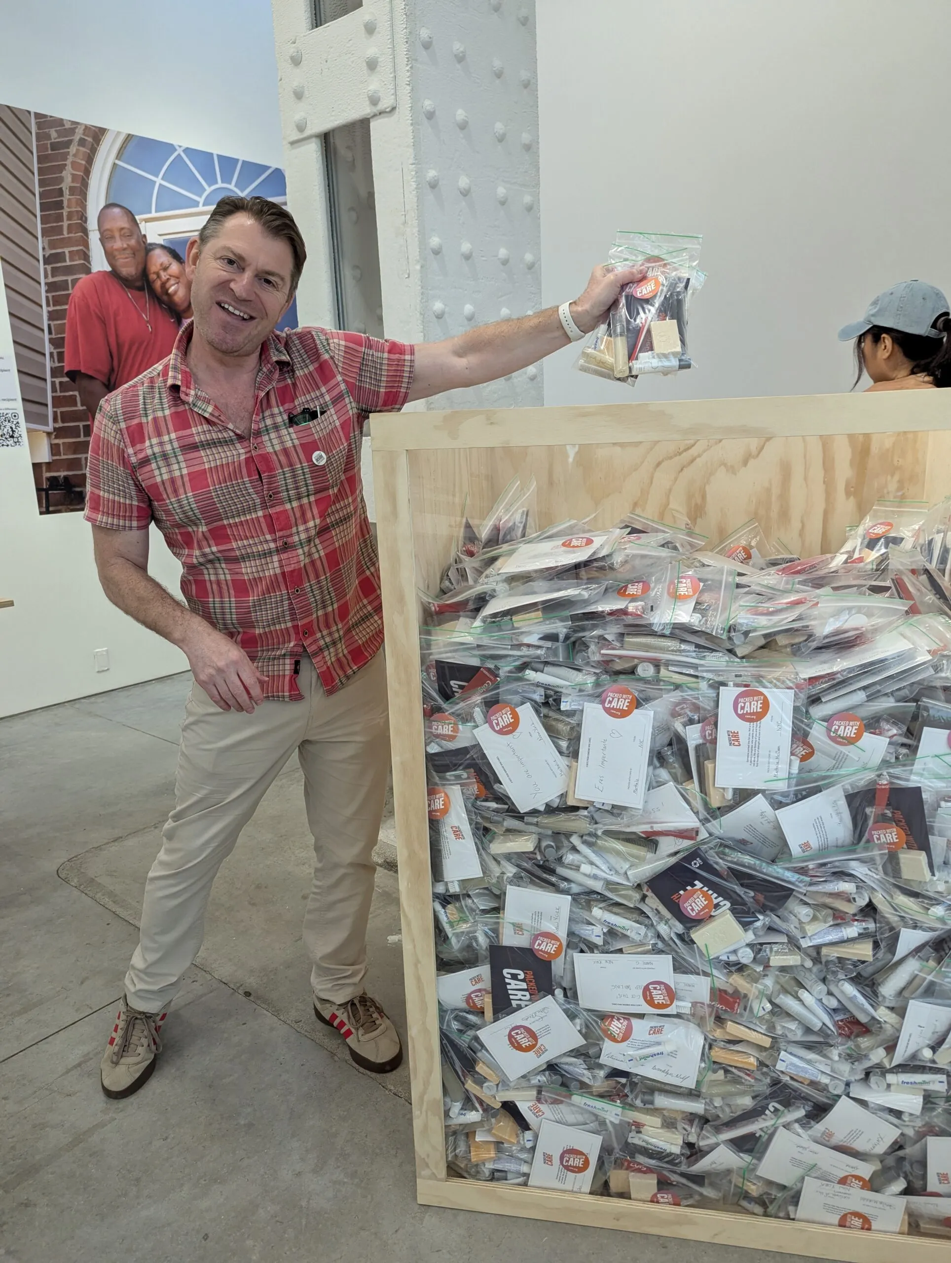 A man standing over a box filled with hygiene kits.