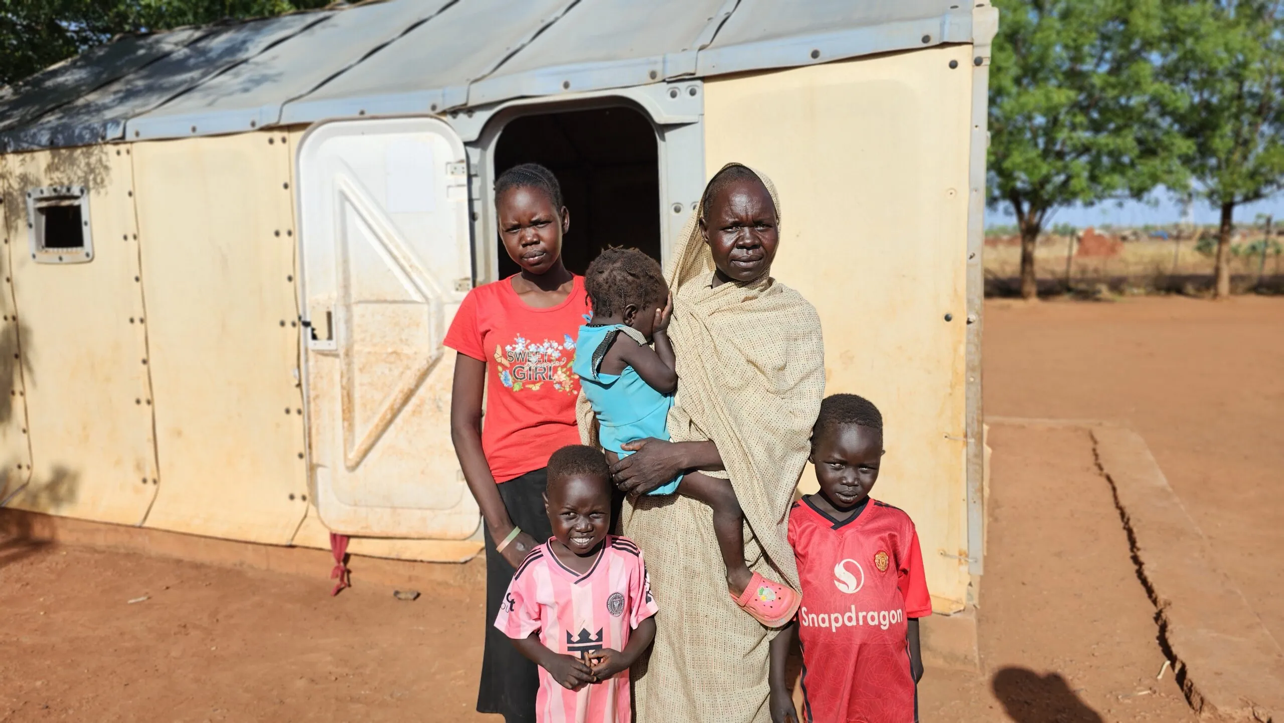 A mother and four children stand in front of a designated sleeping shelter.