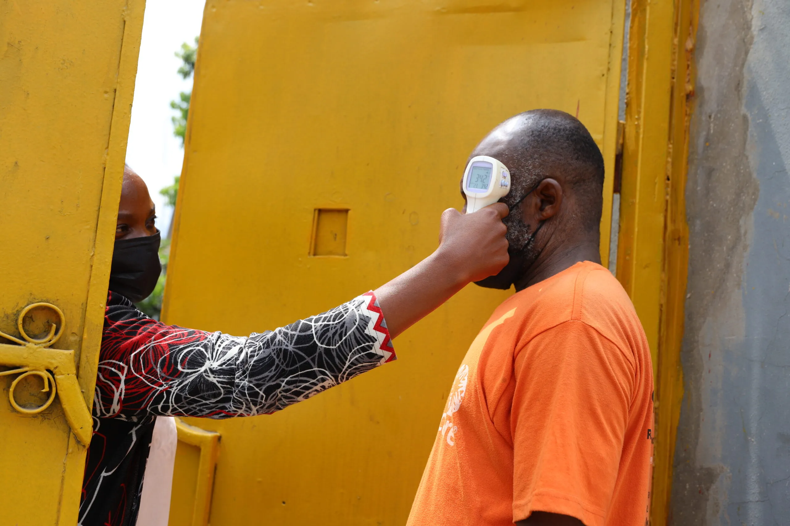 A man standing outside getting his temperature checked.