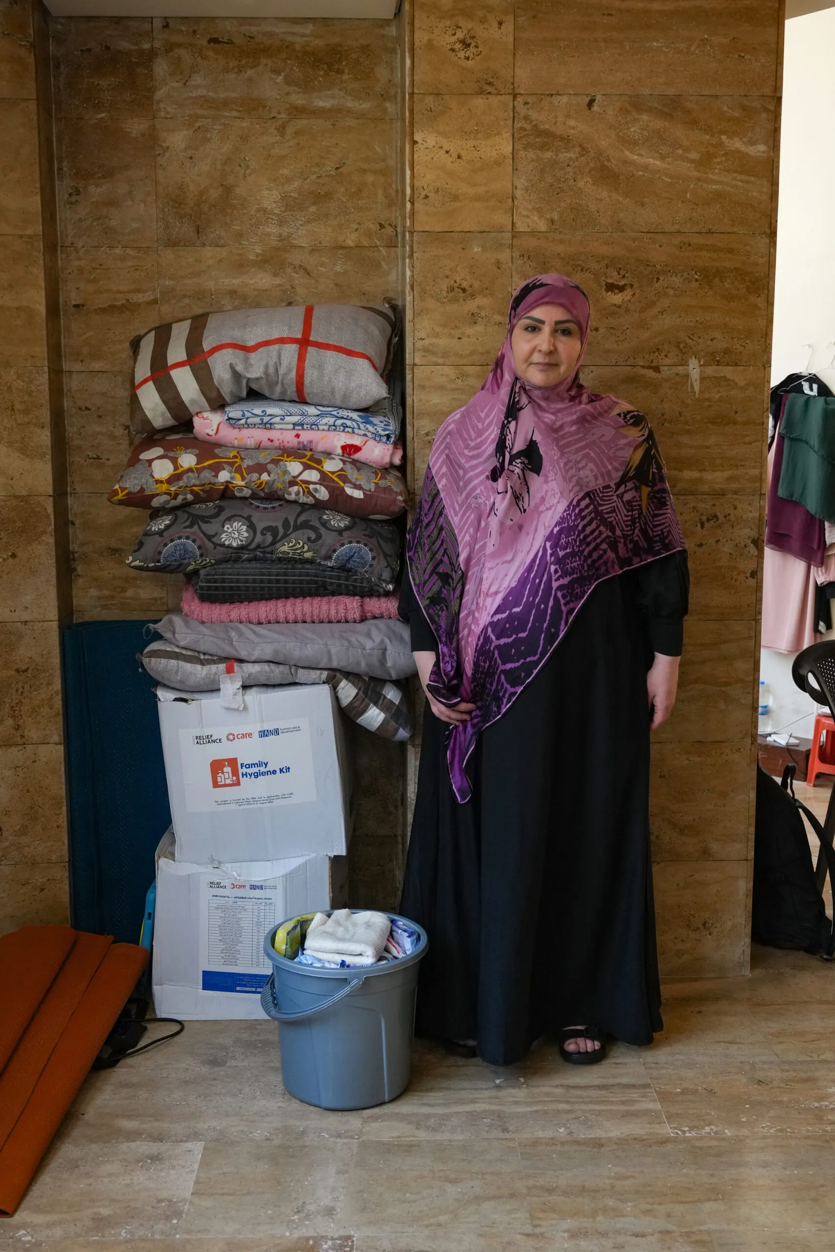 A woman standing next to boxes of supplies and aid she received from CARE.