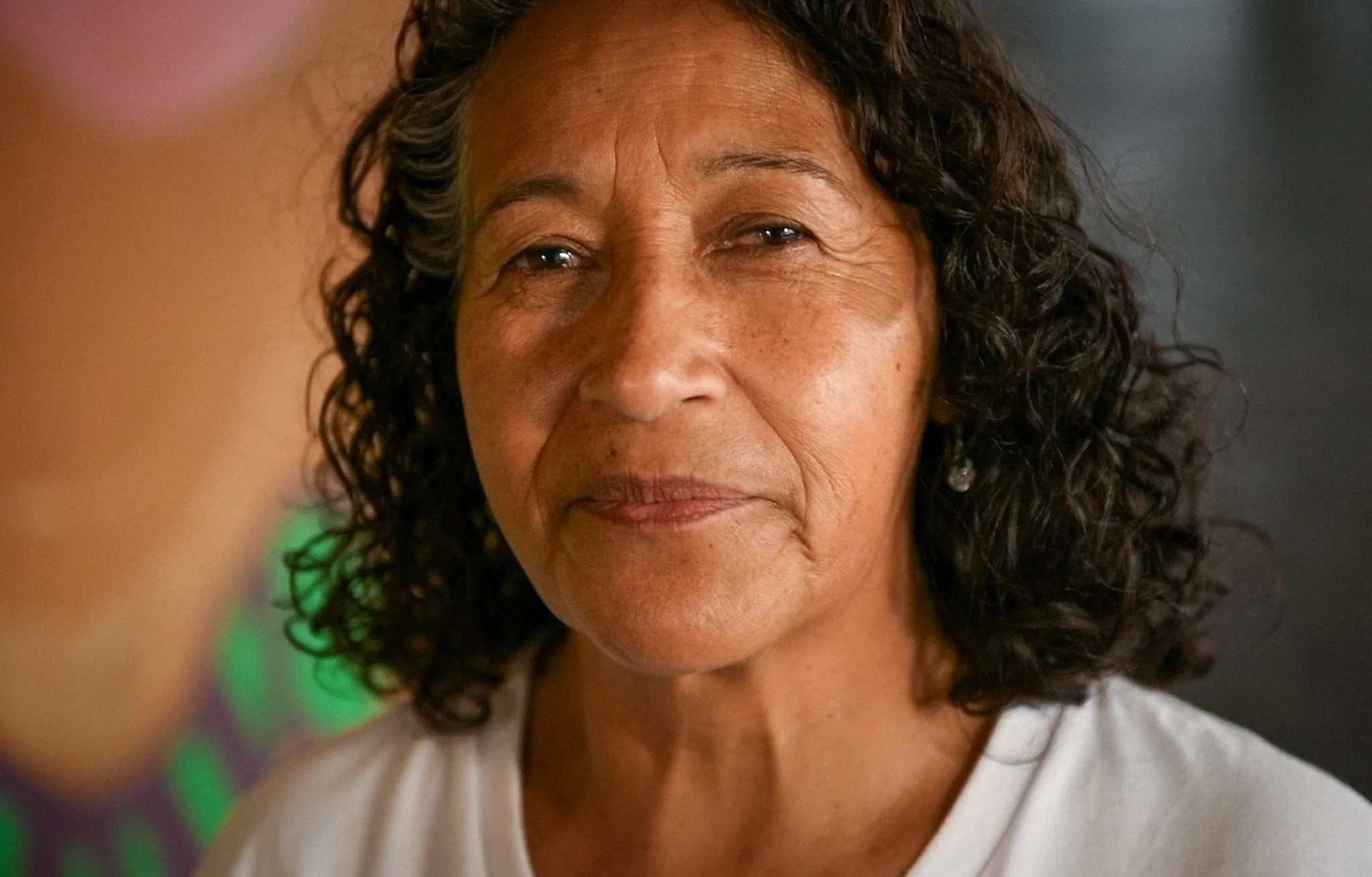 María looks into the camera. She is dignified and calm.