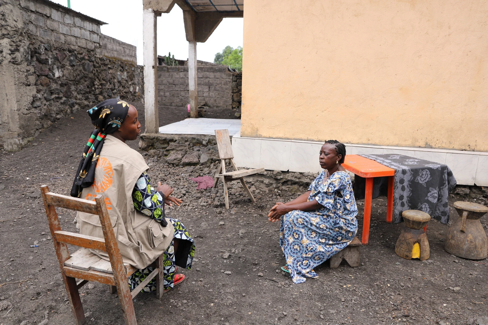 Two women sitting outside talking in rural community in DRC.