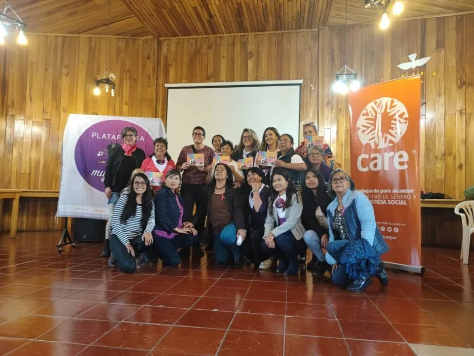A group of people pose for a photograph in front of two banners, one bearing the CARE logo.