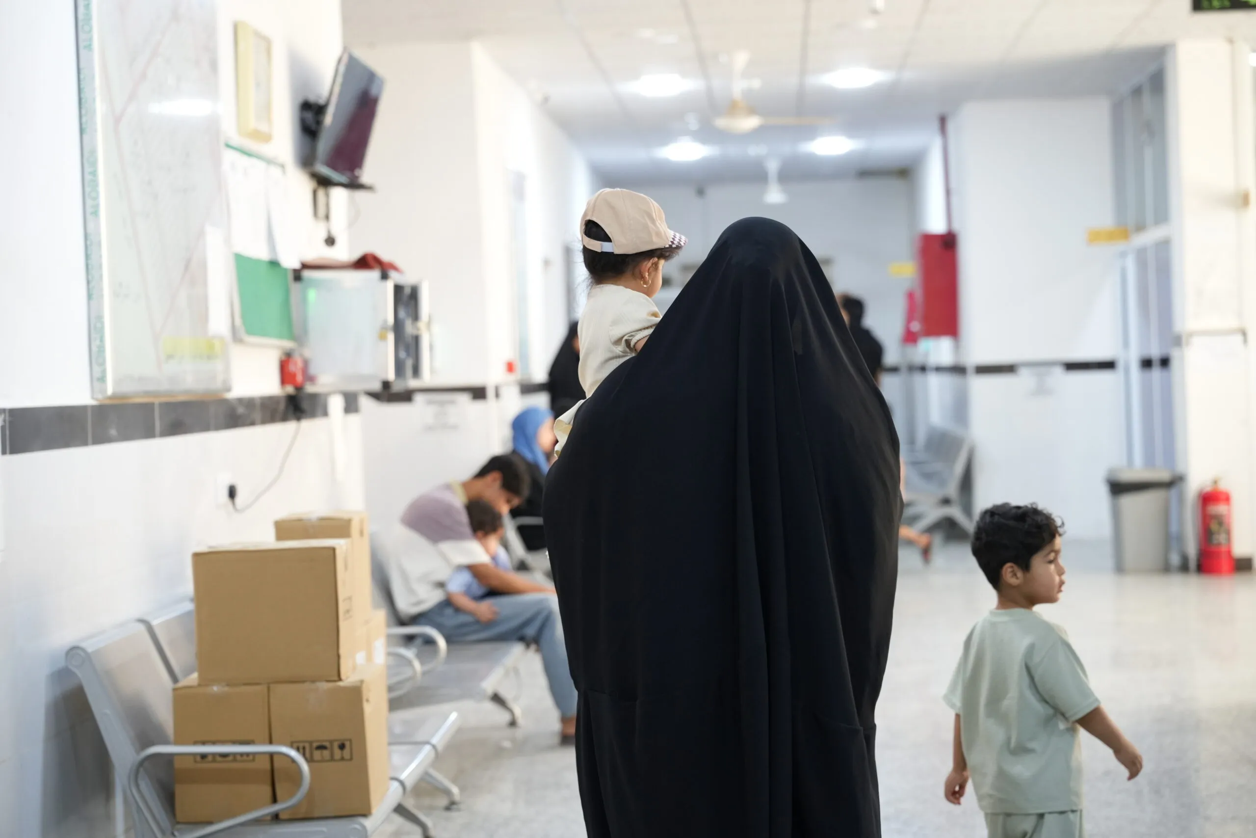 A woman walks through a medical clinic with her two young children.