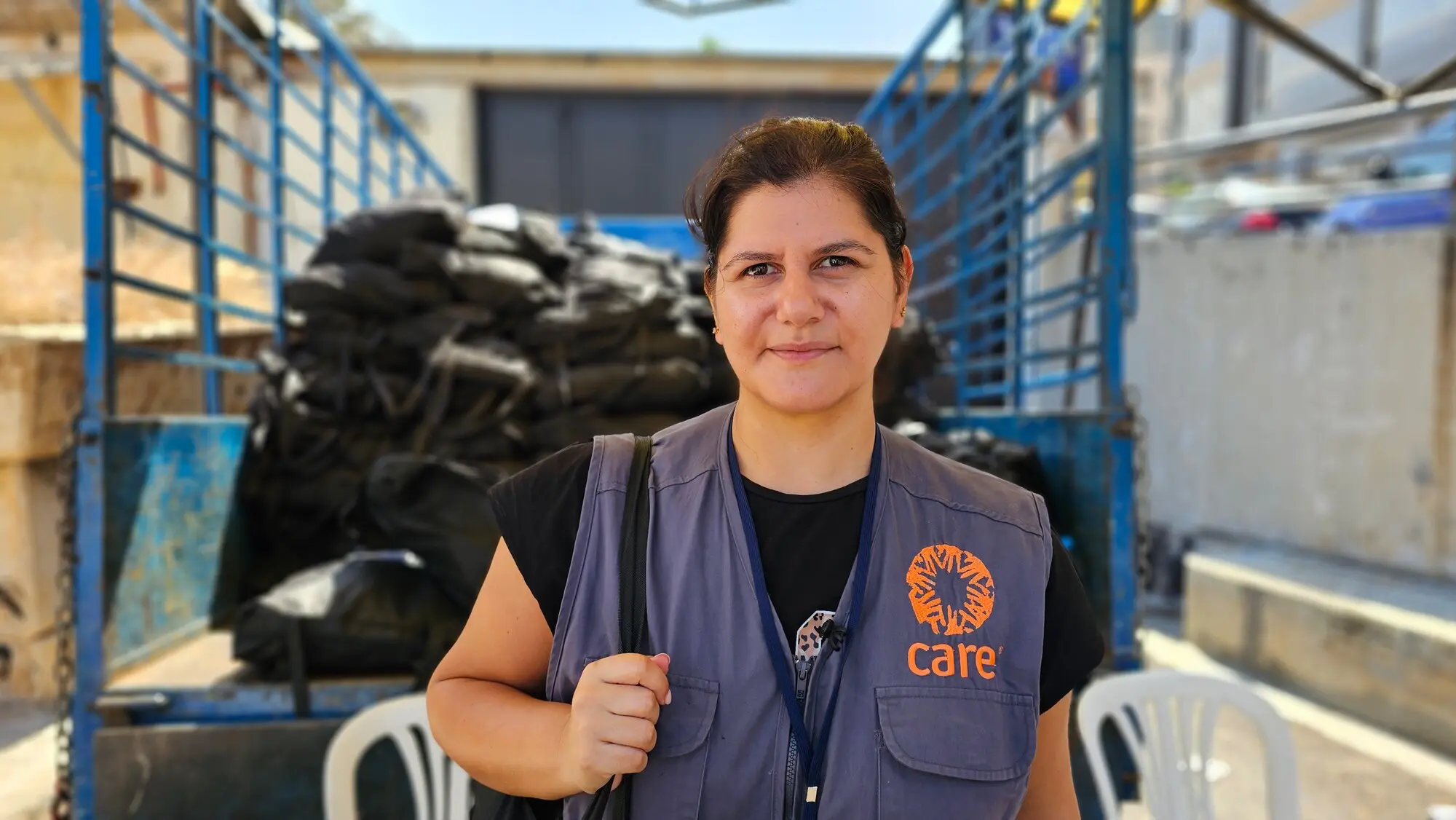Woman aid worker in Lebanon looking into camera with truck in background.