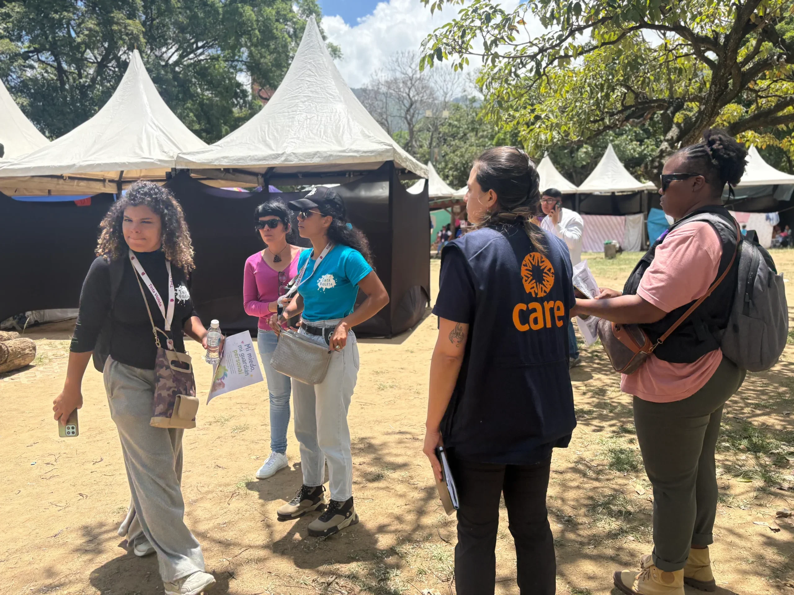 A group of women aid workers gathering in front of tent shelters.