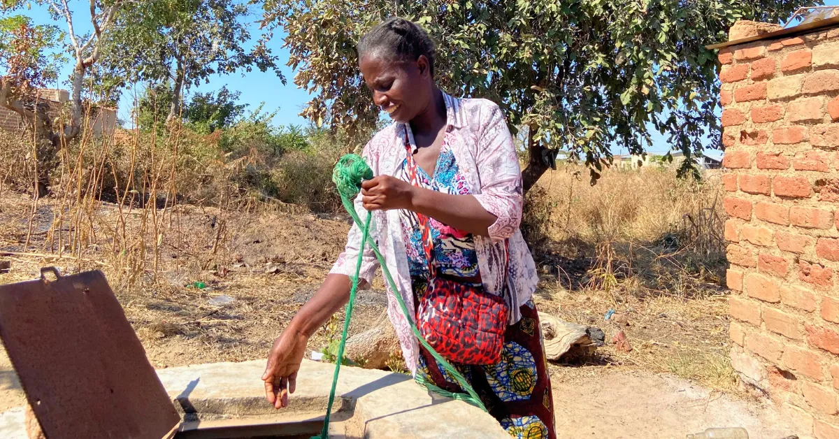 A woman inspecting a household sanitation facility.