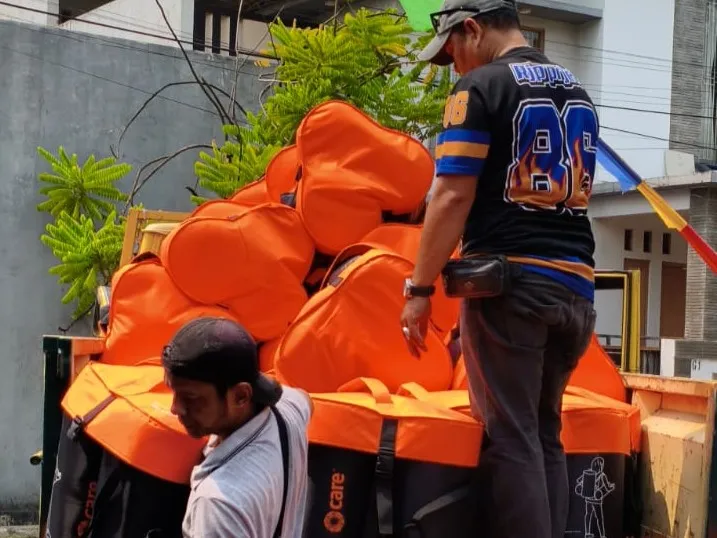 Two men unloading bright orange emergency relief packages in Indonesia.