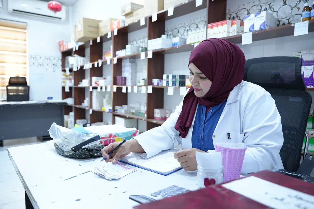 Marwa Hayman, a health worker at a pharmacy in Basra, Iraq, reviews patient records at her desk as part of CARE's Mother Care Project.