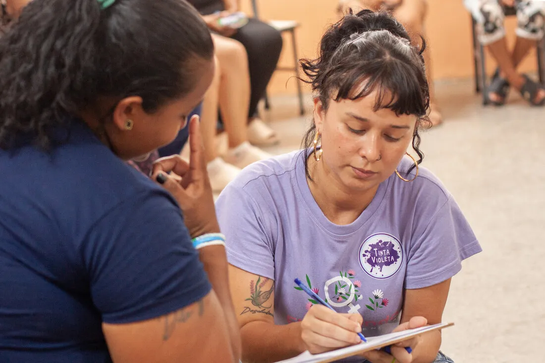 A CARE and Tinta Violeta team member takes notes while a woman shares information during a support session at Campamento Armando Reverón in Catia la Mar, La Guaira, Venezuela, following the earthquakes.