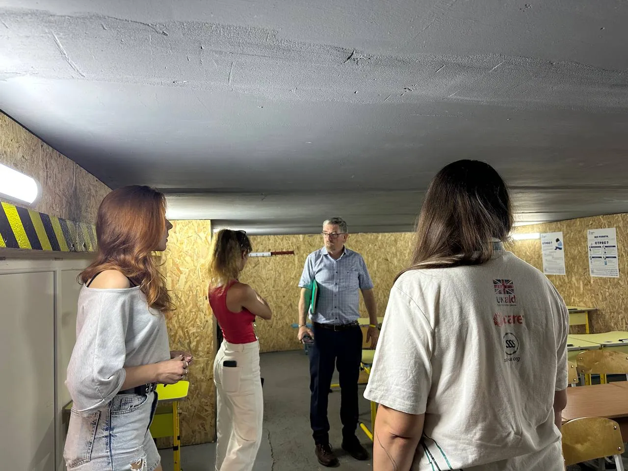 A group of people gathered in a makeshift classroom in a shelter in Ukraine.