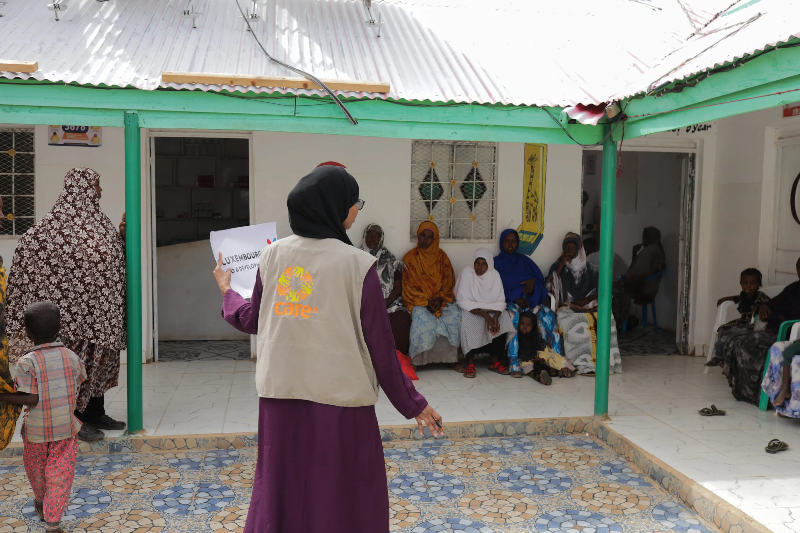A healthcare worker in a CARE vest helps families at a health clinic in Somaliland.