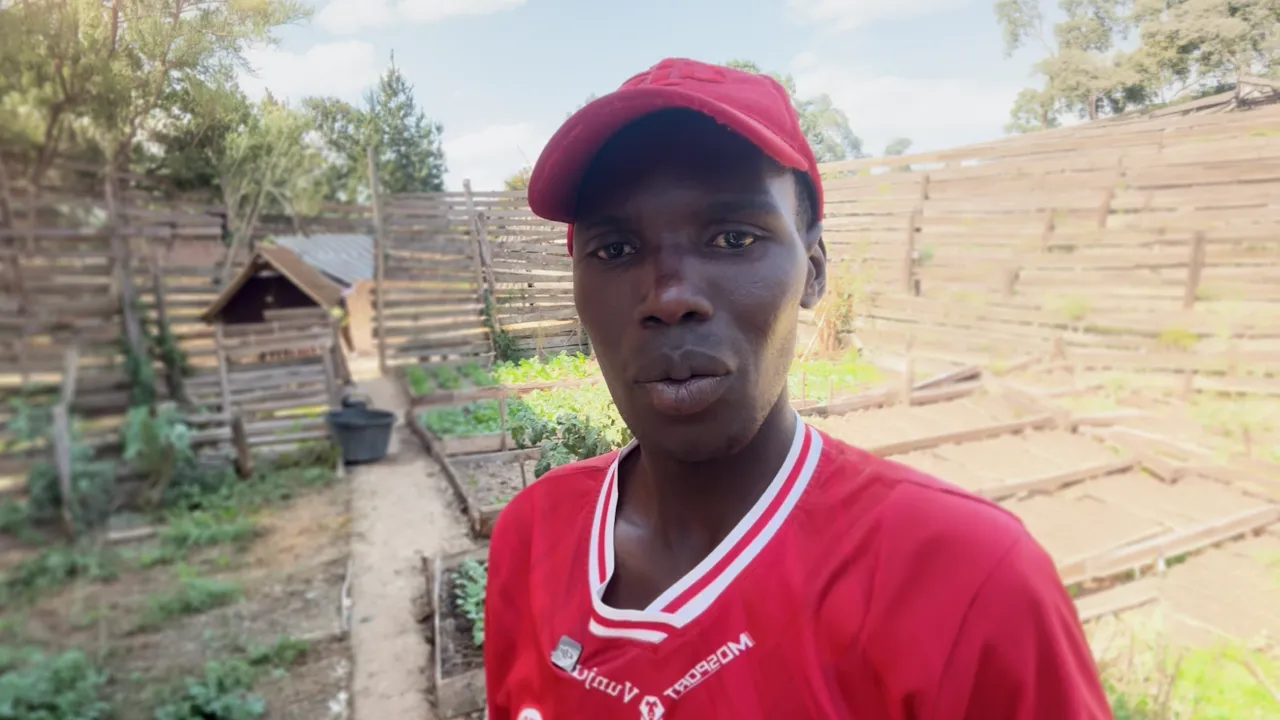 Man in red hat standing in front of a tree nursery in Tanzania.