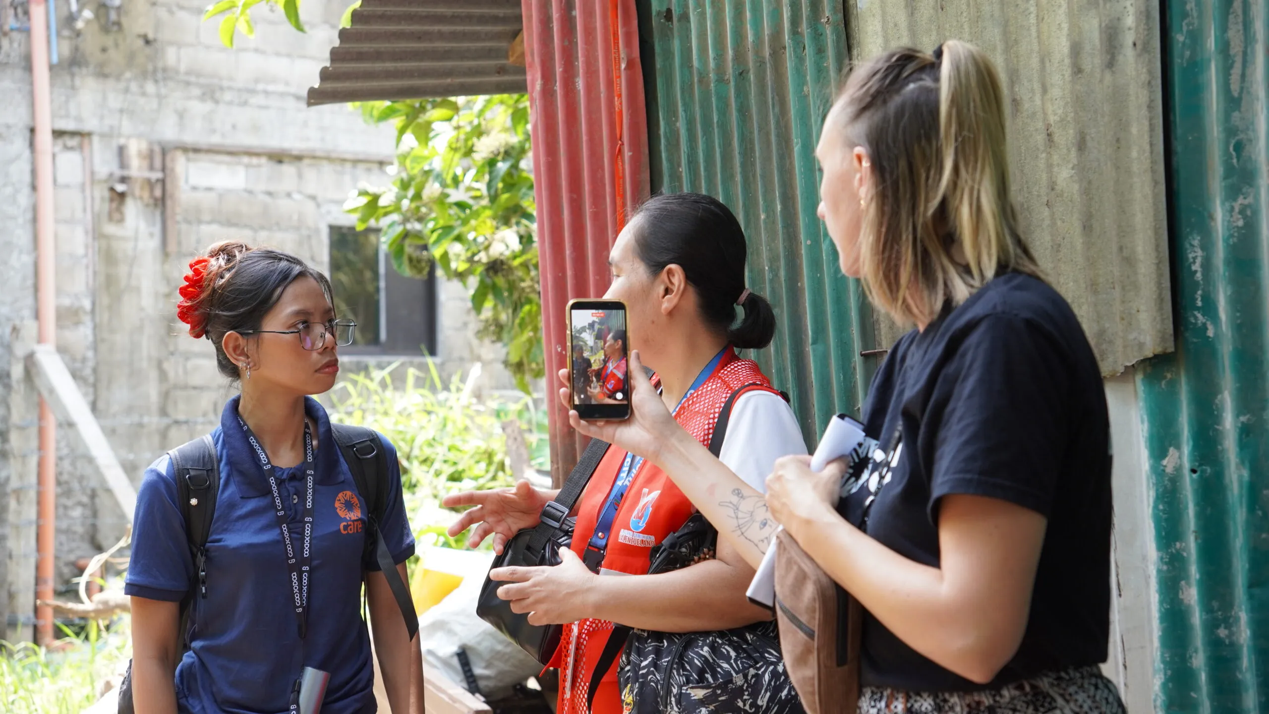 Three women in street wearing medical vests and CARE t-shirts.