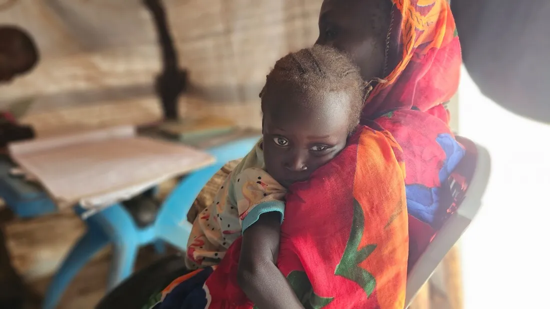 A young South Sudanese girl hugs her mother.