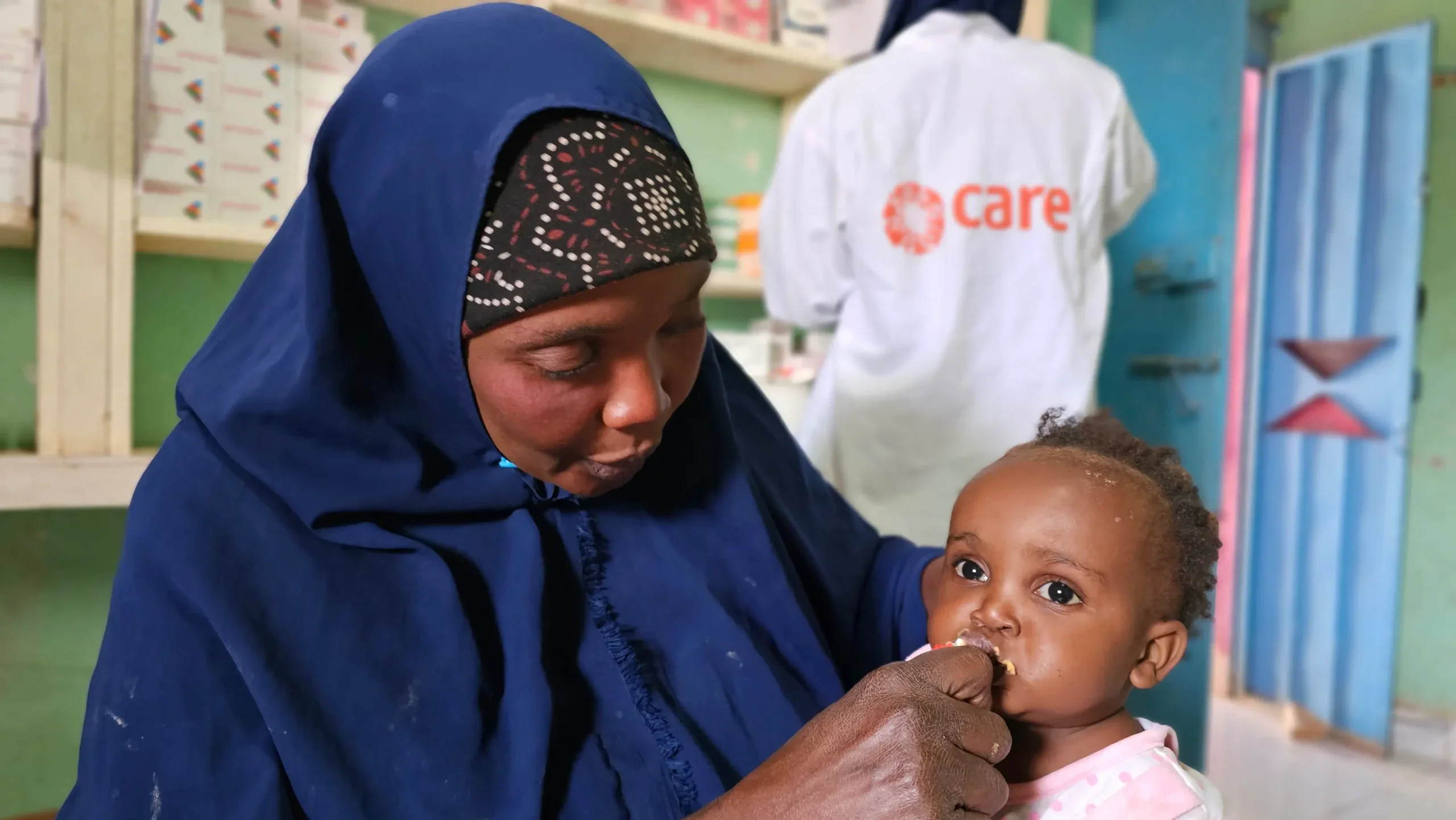 A mother feeding her baby therapeutic food in a CARE health center.