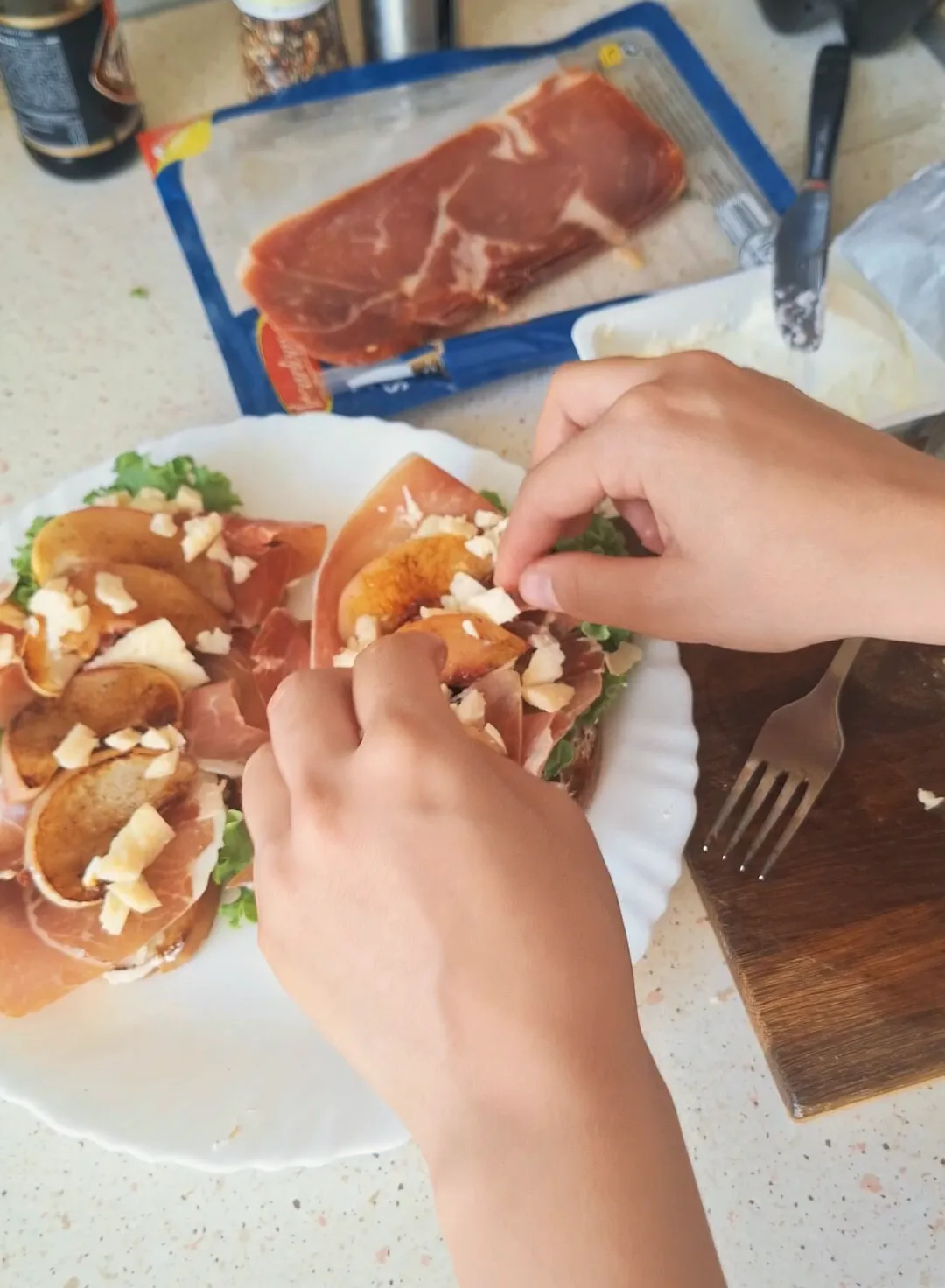Svitlana’s hands prepare a breakfast sandwich on a kitchen counter.
